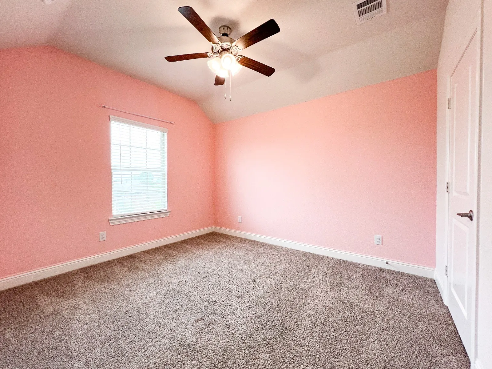 Vaulted ceiling with a ceiling fan, window with blinds, carpet flooring, and a white interior door