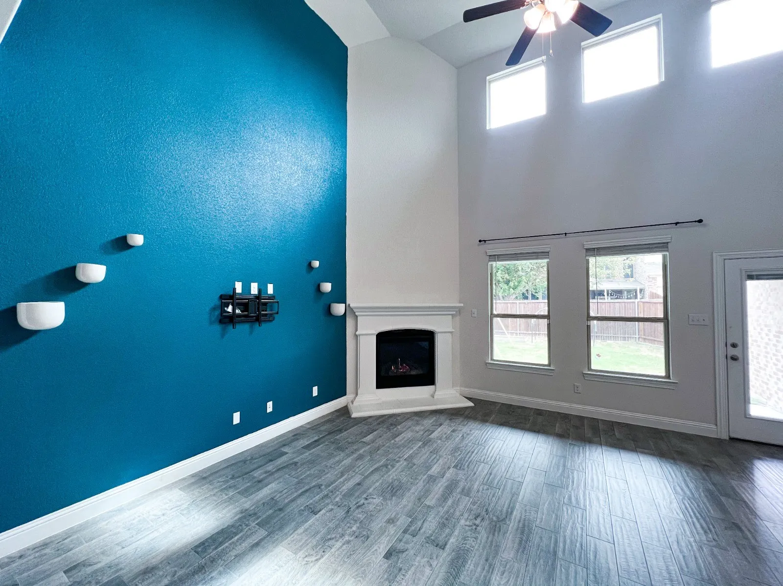 Soaring ceiling, wood-finish flooring, corner fireplace, transom windows, ceiling fan with integrated lighting