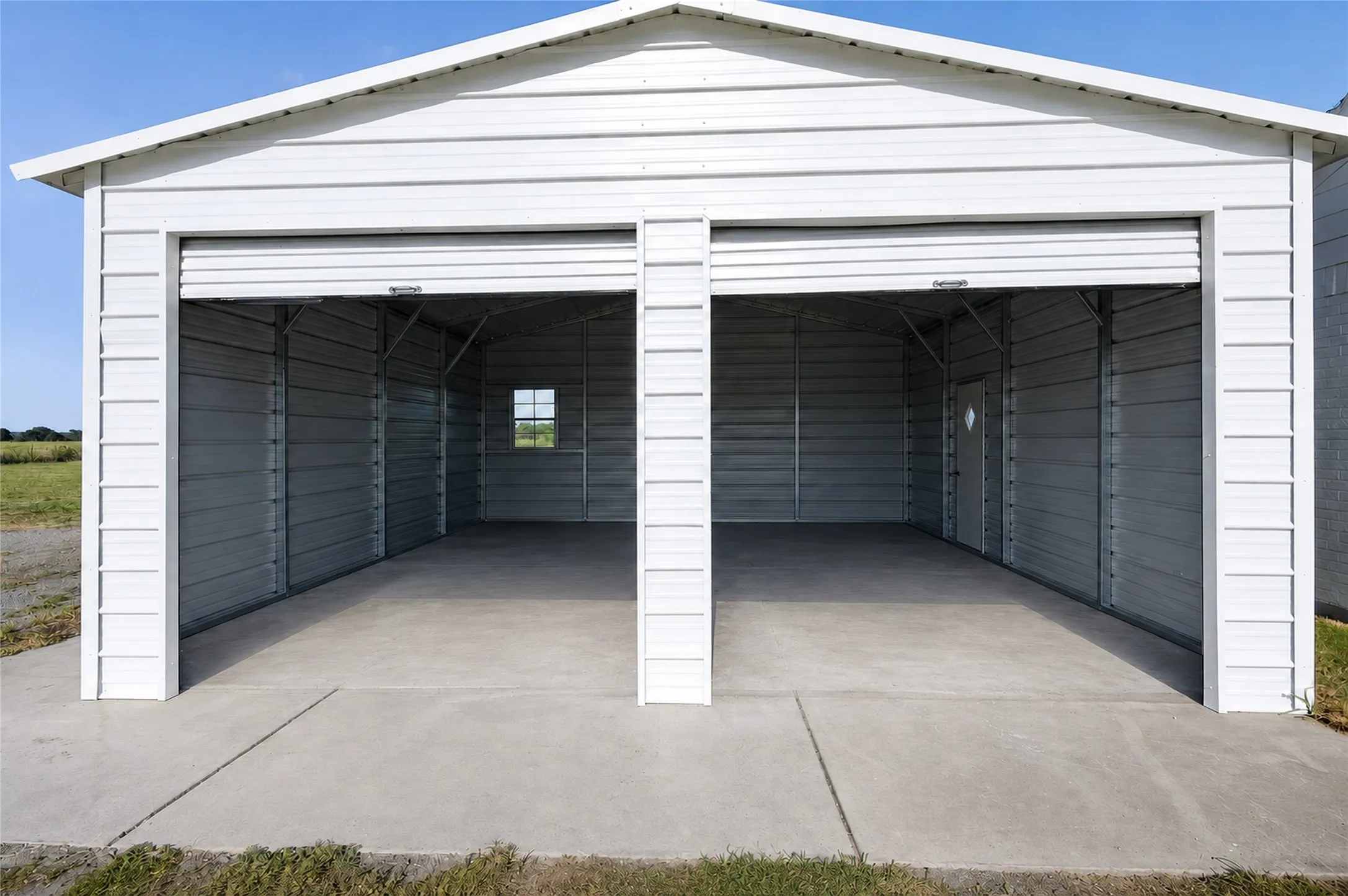 White metal two-bay garage structure with roll-up doors, concrete flooring, and interior metal framing
