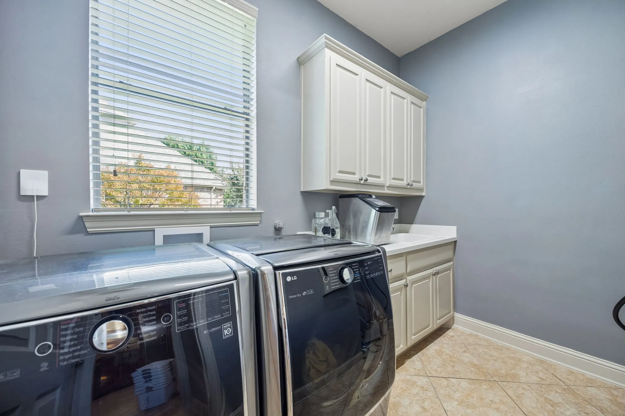 Spacious laundry room with sink and built in cabinetry. Opposite wall has an outlet for an add'l fridge or freezer