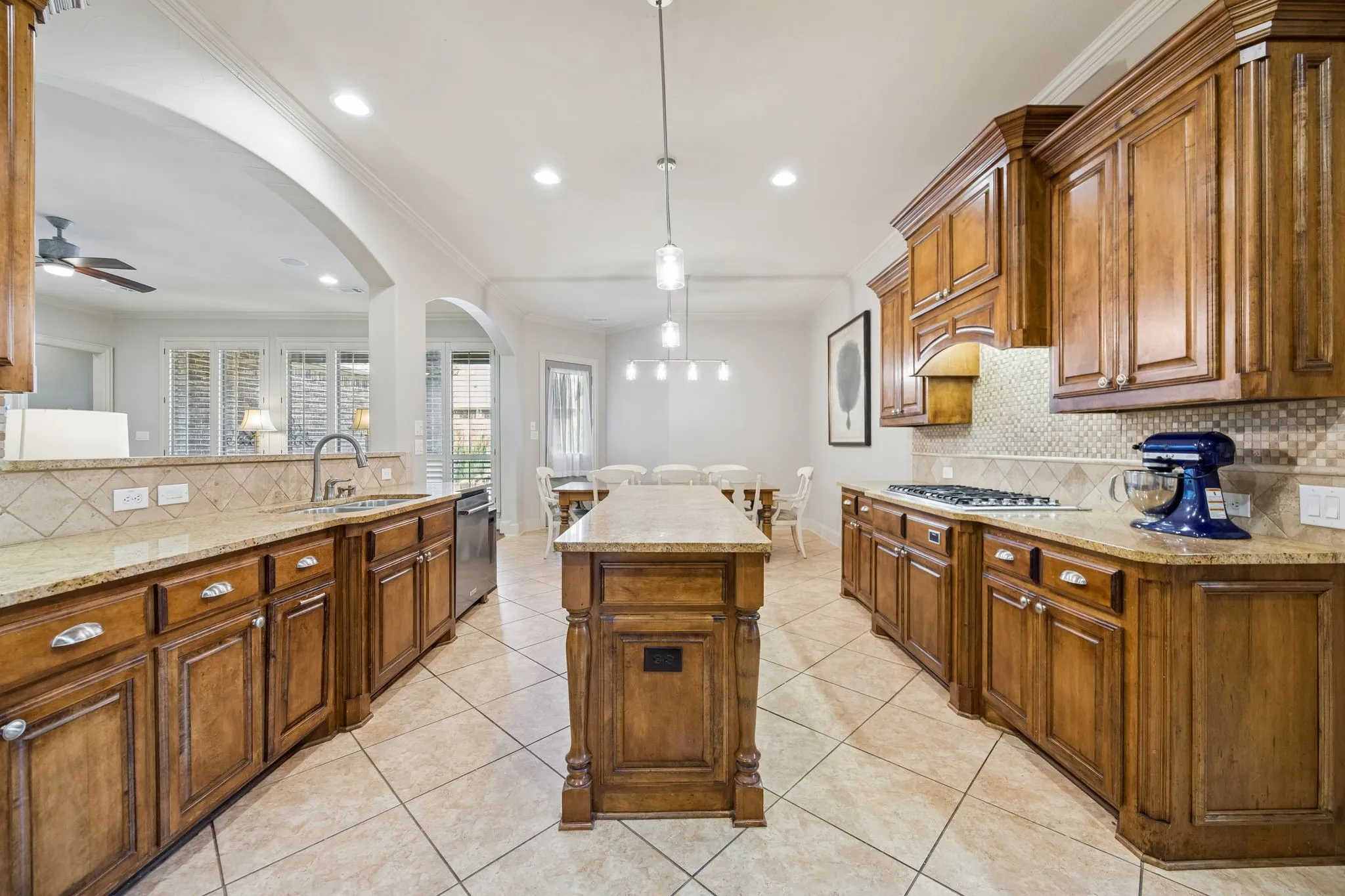Long center island with pendant lighting, solid wood cabinetry, granite countertops and a Viking 6 burner gas cooktop