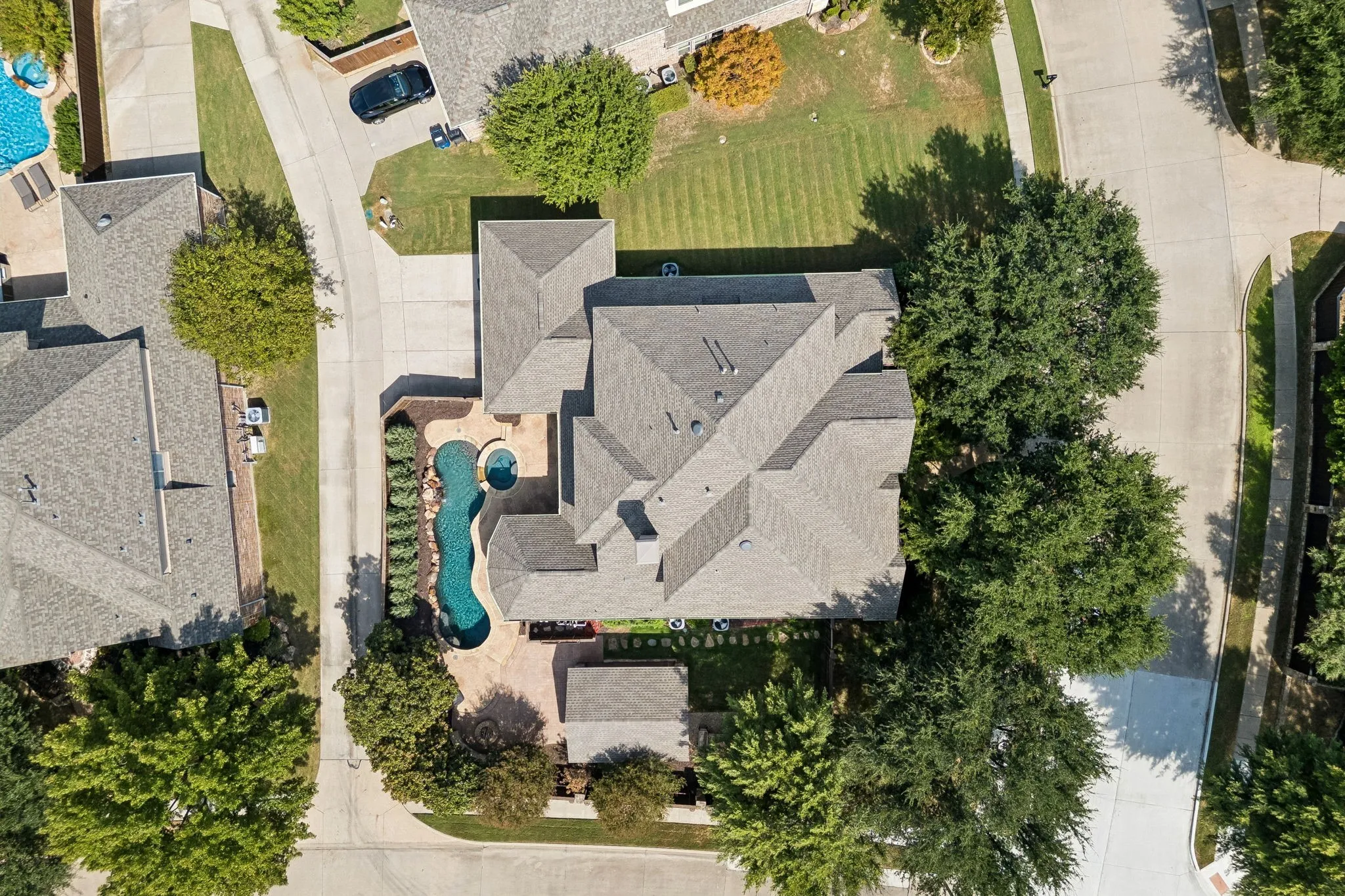 Corner lot with mature trees, curved swimming pool with an spa, surrounded by a paved patio, and side yard with large covered gazebo space