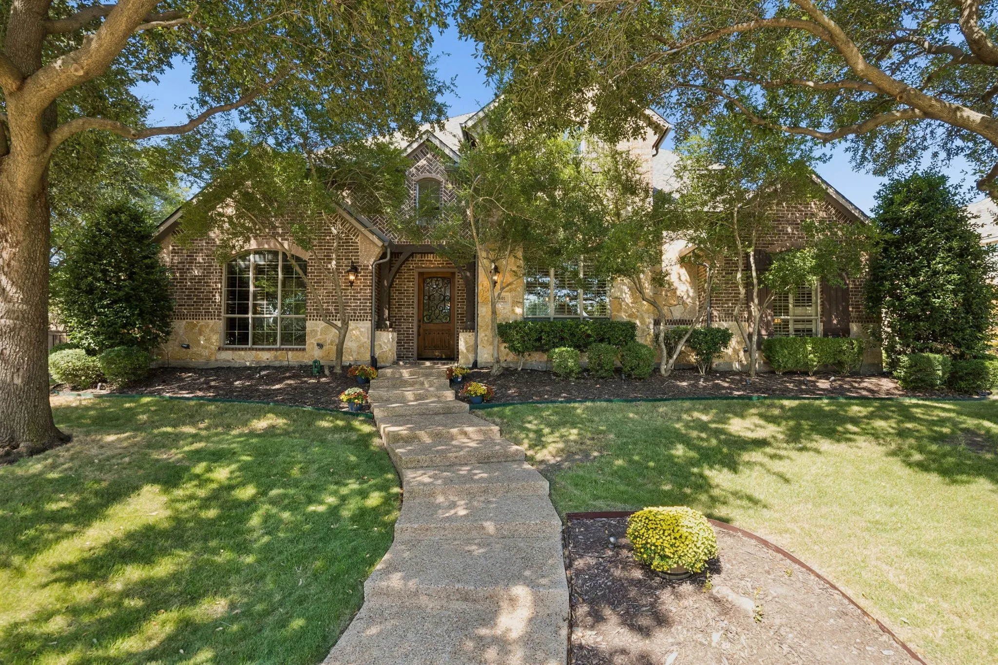 Sanders Custom built home with stone and brick arched entry, prominent front door, and a curved concrete pathway