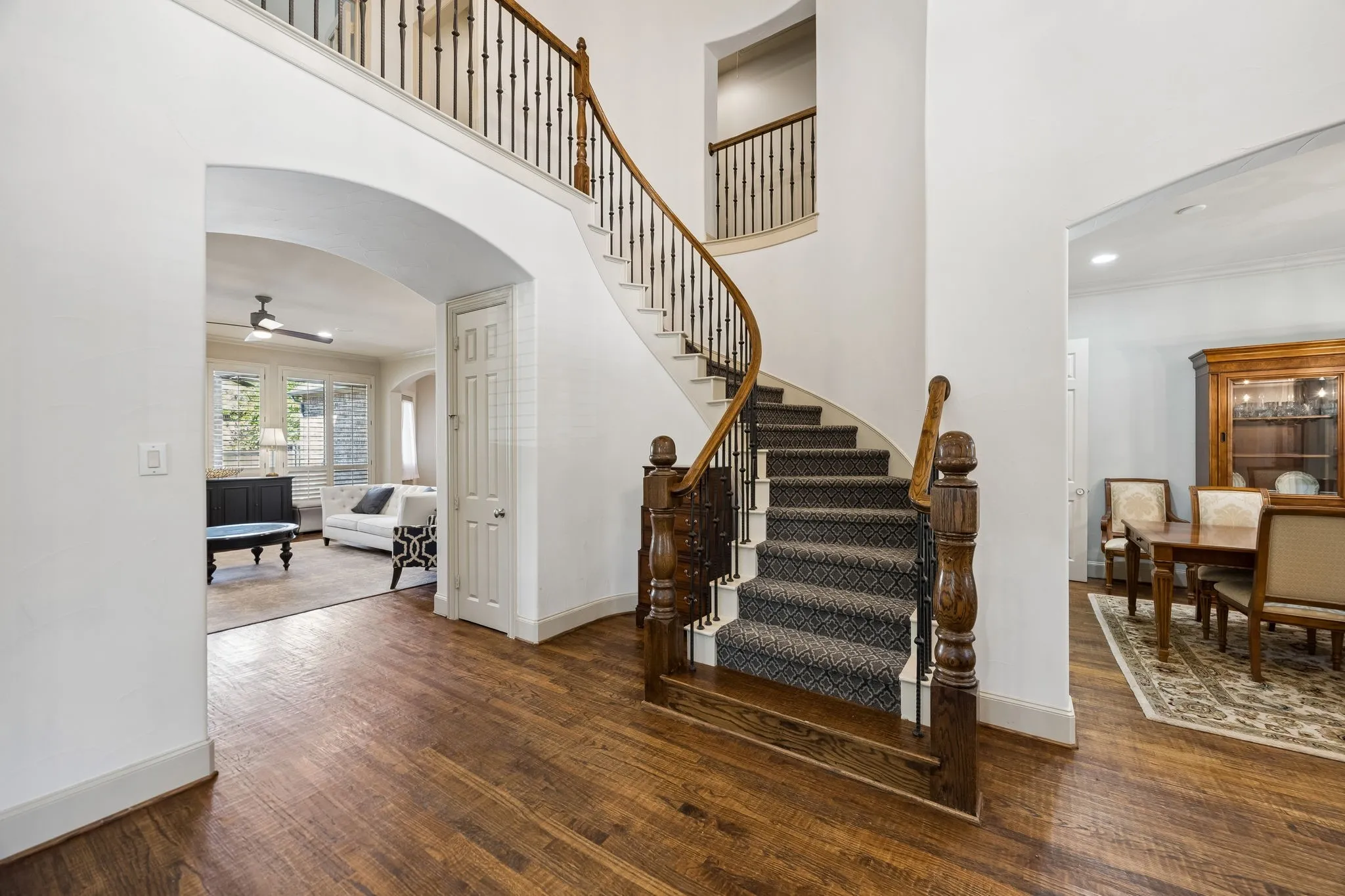 Grand curved staircase with custom carpet, iron balusters