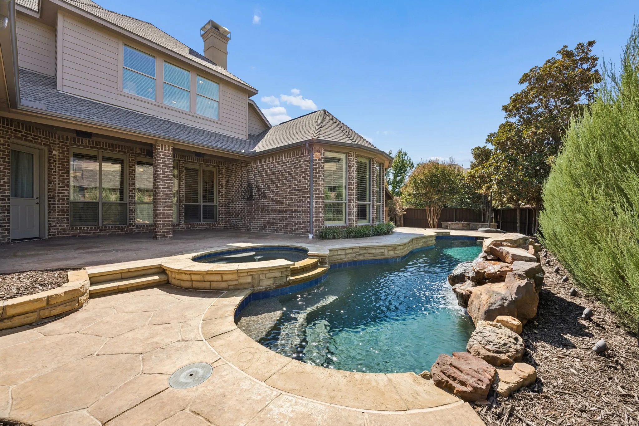 Pool and Spa, with salt water system updated in 2026. Rock waterfall feature and a large stamped concrete patio
