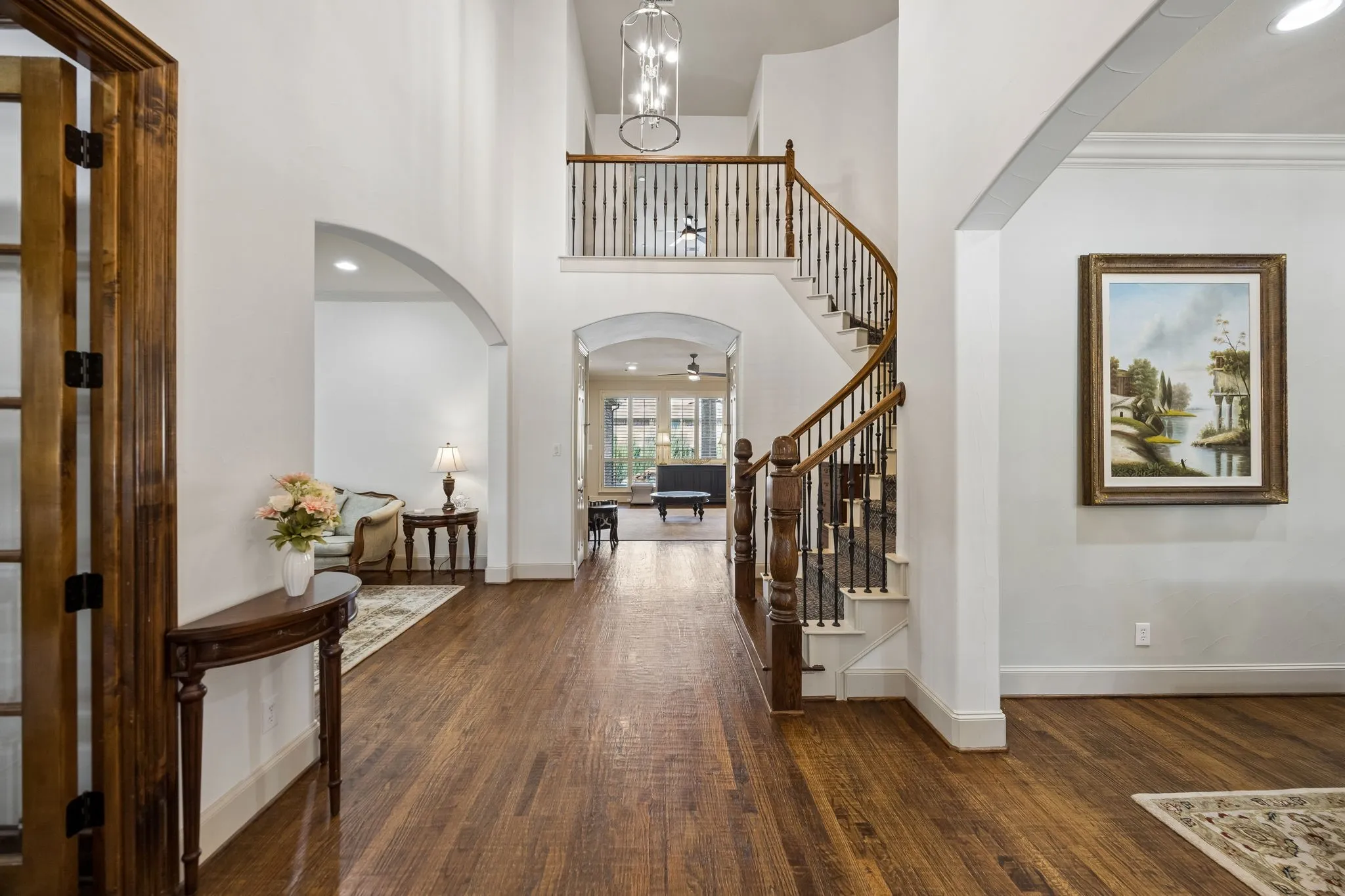 Two-story foyer with hand-scraped wood flooring, dramatic curved staircase featuring and wrought iron balusters