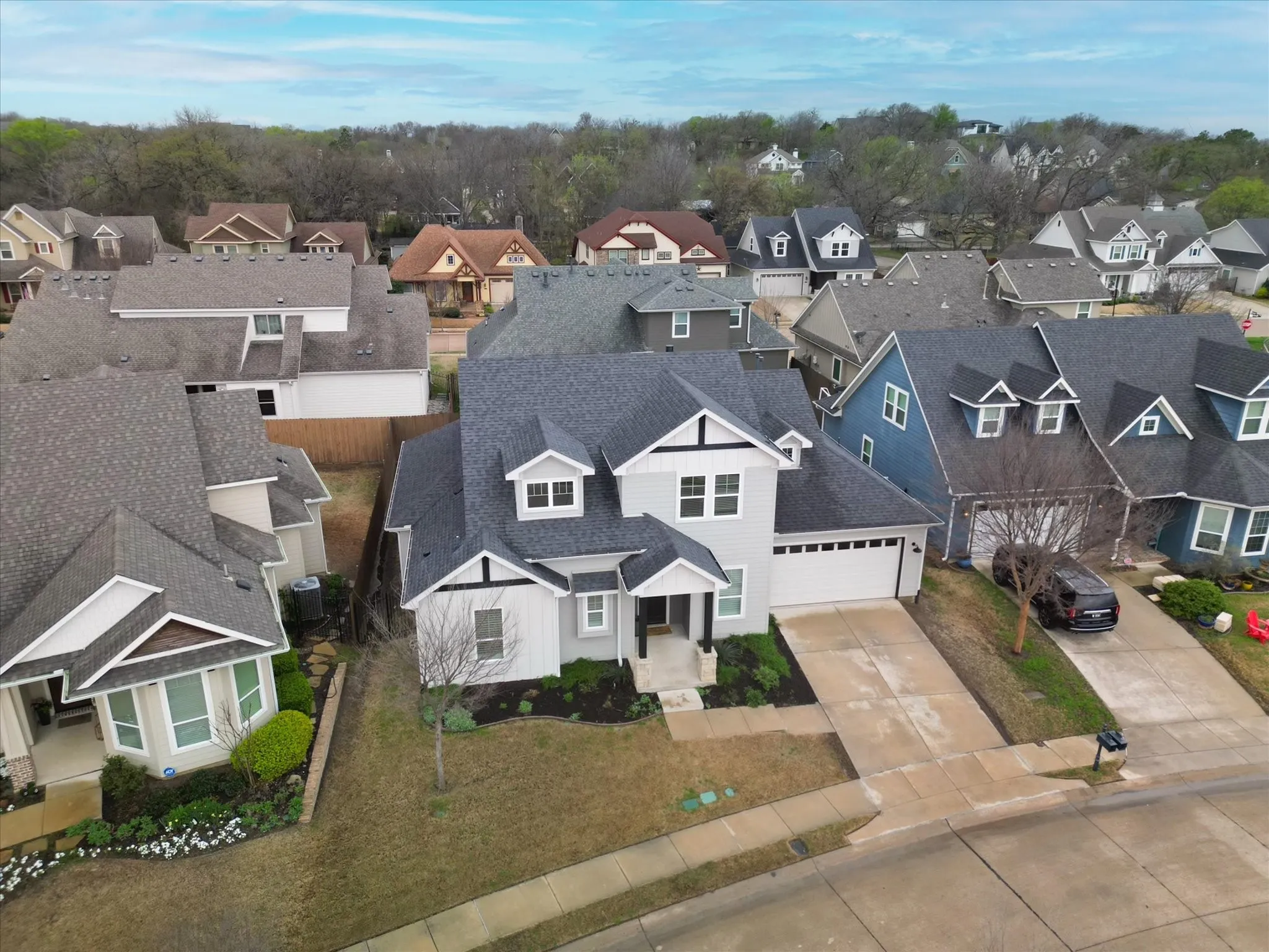 Two-story residence with a light gray exterior, dark gray shingle roof, and a two-car garage