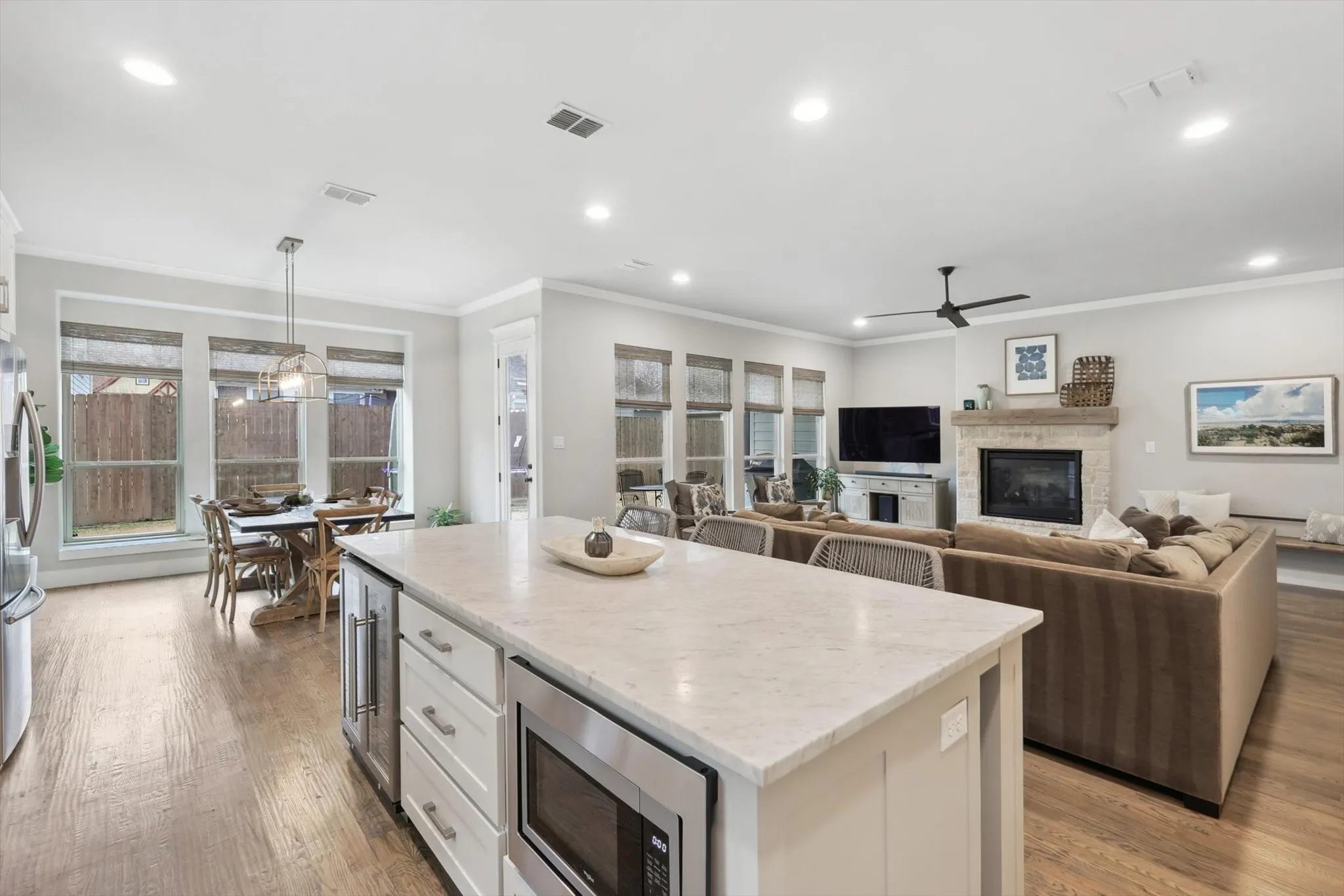 Kitchen island with white cabinetry, built-in microwave, and beverage refrigerator