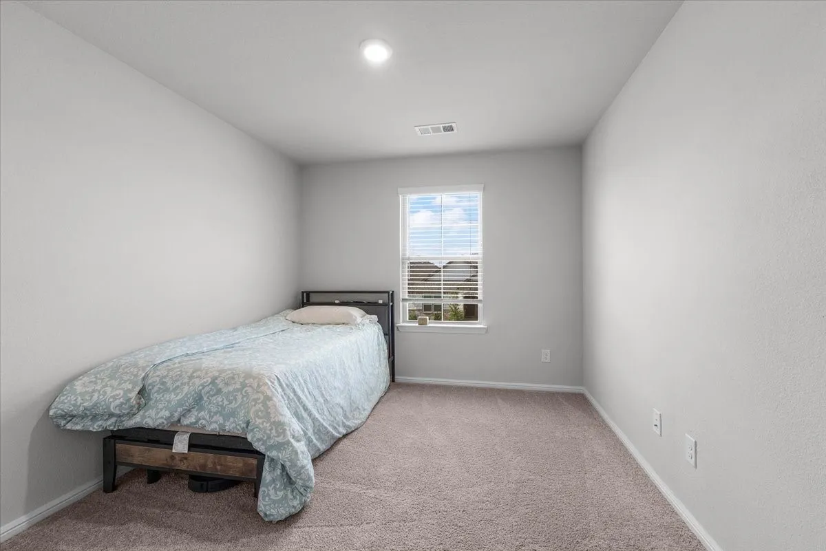Recessed ceiling light, neutral carpet flooring, and window with blinds