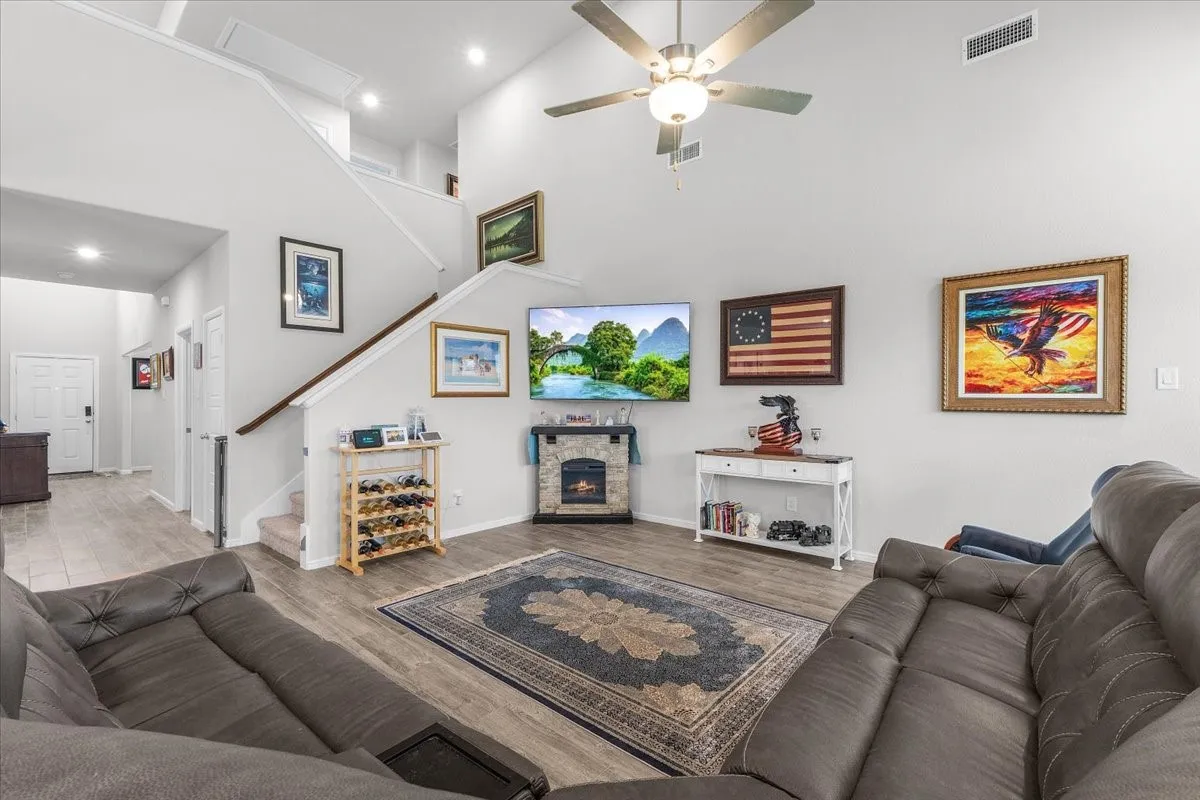 Vaulted ceiling, ceiling fan, recessed lighting, wood-finish flooring, and a built-in fireplace feature