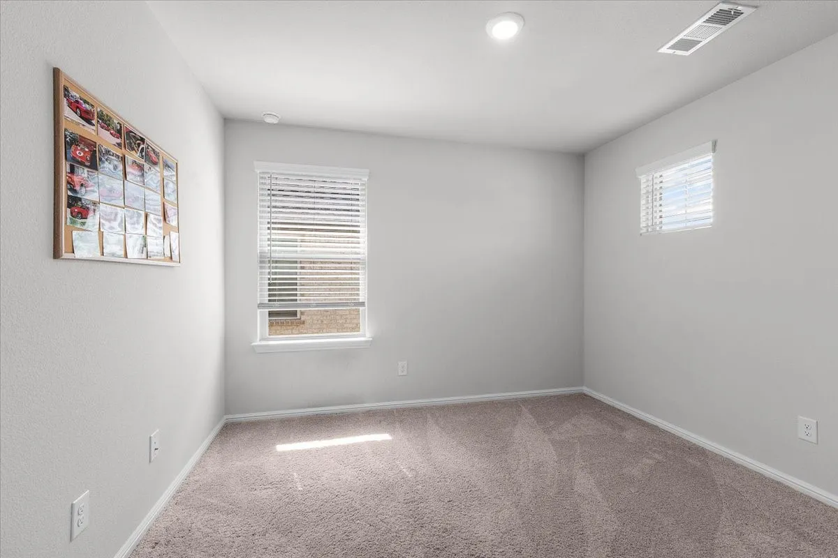 Neutral-toned carpet flooring, two windows with blinds, recessed ceiling lighting, and a ceiling air vent