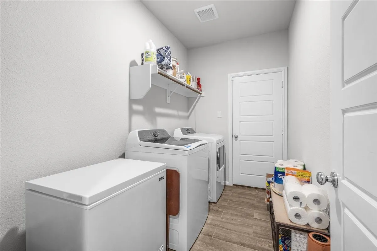 Laundry area featuring wood-finish flooring, overhead shelving, and a paneled interior door