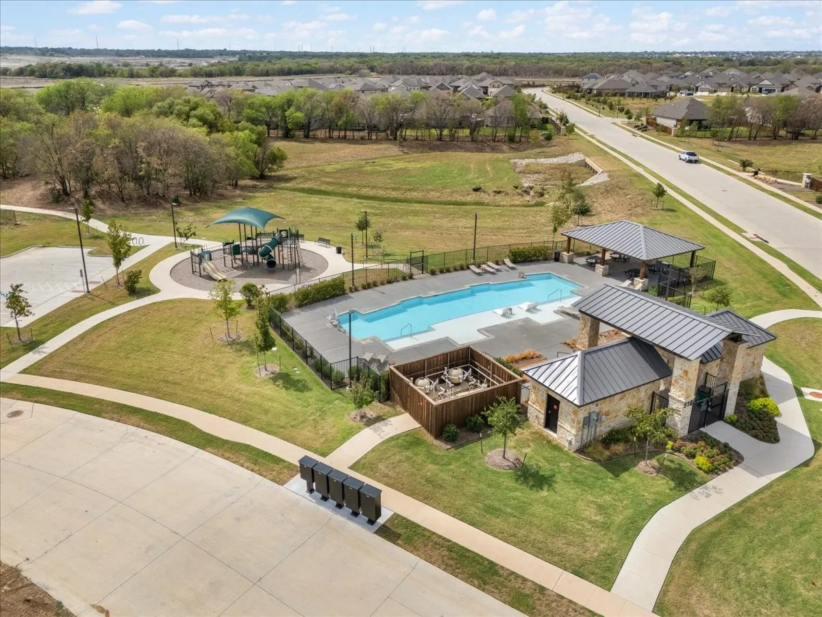 Community amenity center featuring a swimming pool, shaded lounge area, and playground
