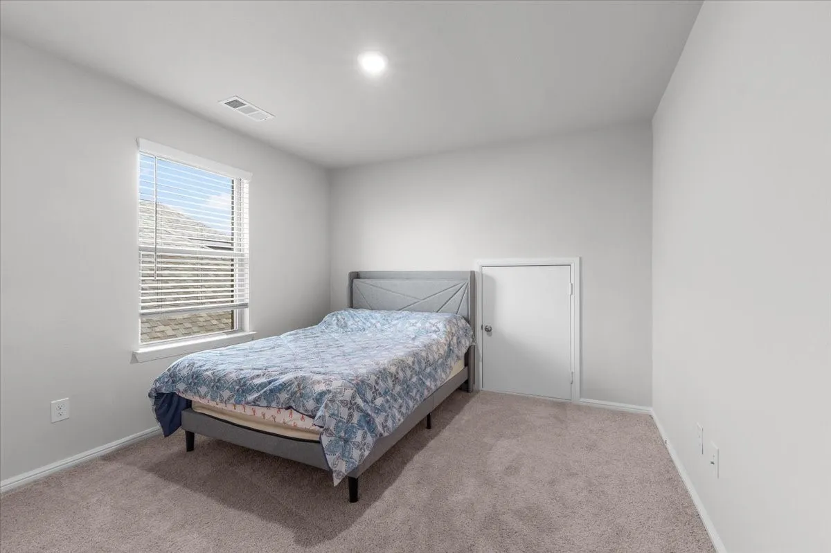 Neutral wall color, window with blinds, carpeted flooring, recessed lighting, and a white interior door