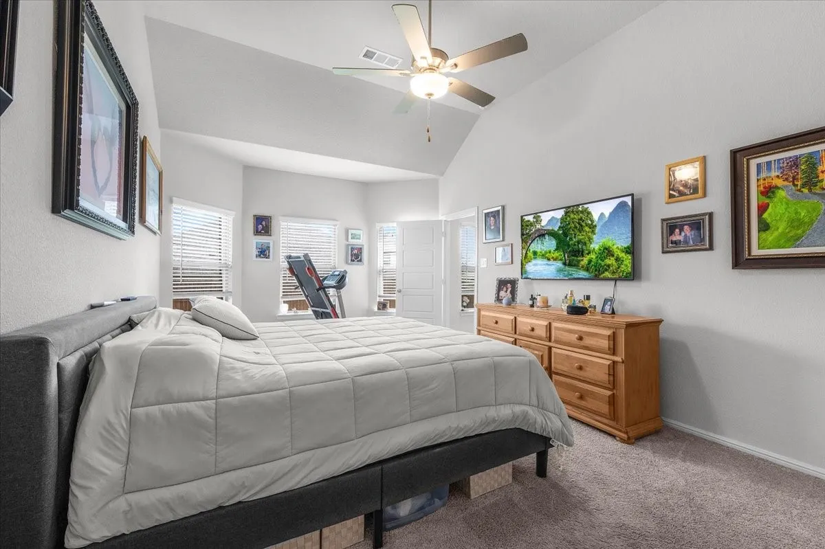 Vaulted ceiling with a ceiling fan, light gray wall paint, and gray carpet flooring