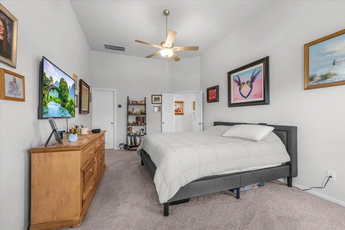 Vaulted ceiling with a ceiling fan, light gray wall paint, and gray carpeting