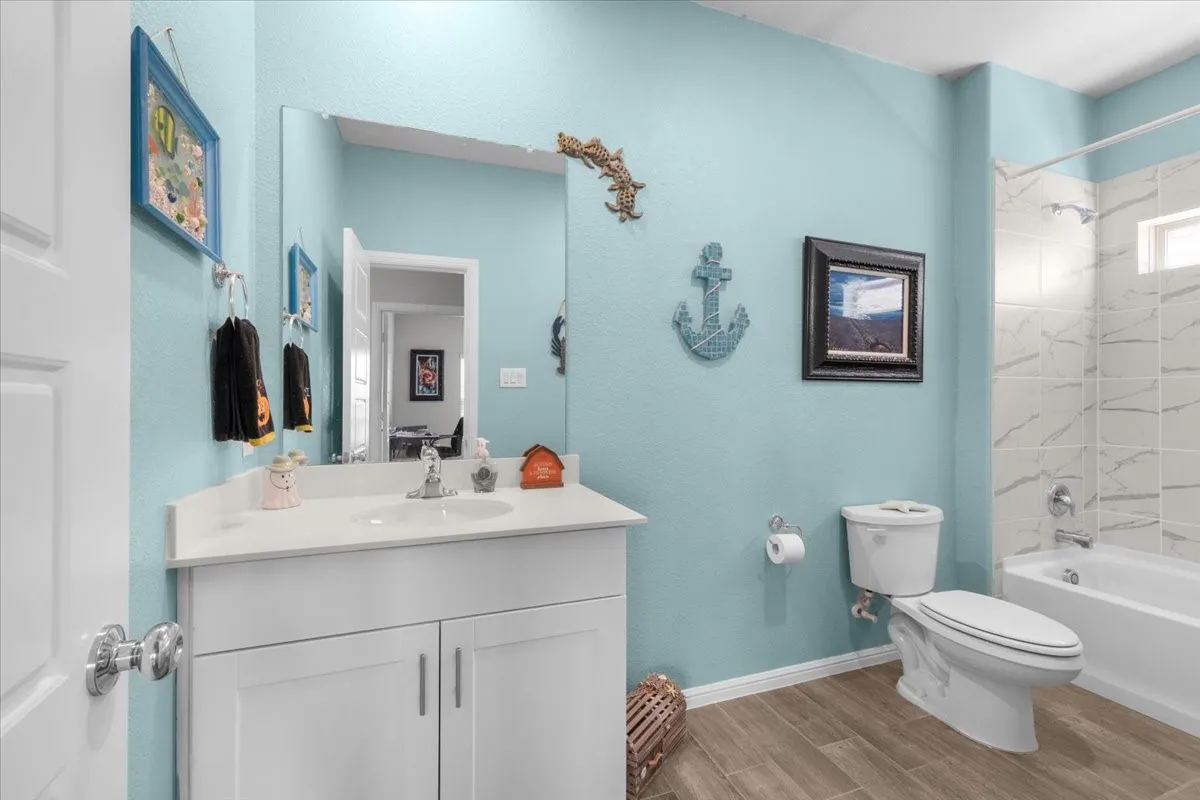 White vanity with an integrated sink, polished chrome faucet, and wood-finish flooring