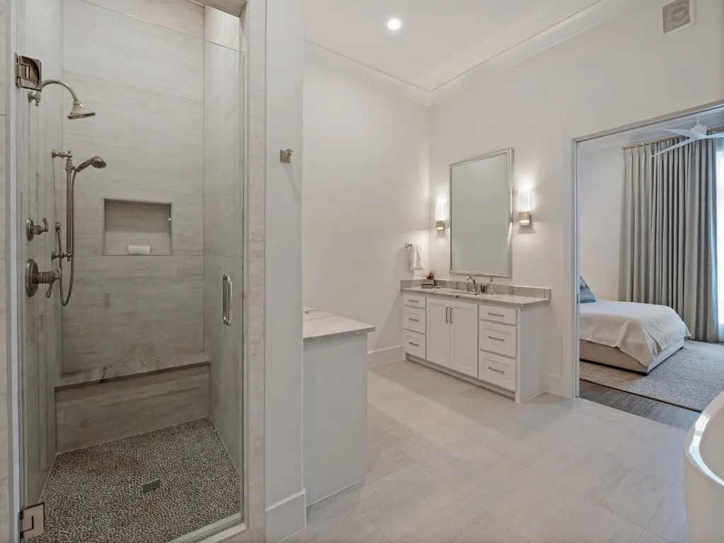 The walk in shower is large with a bench, hand held sprayer or shower head, and a convenient niche for products.