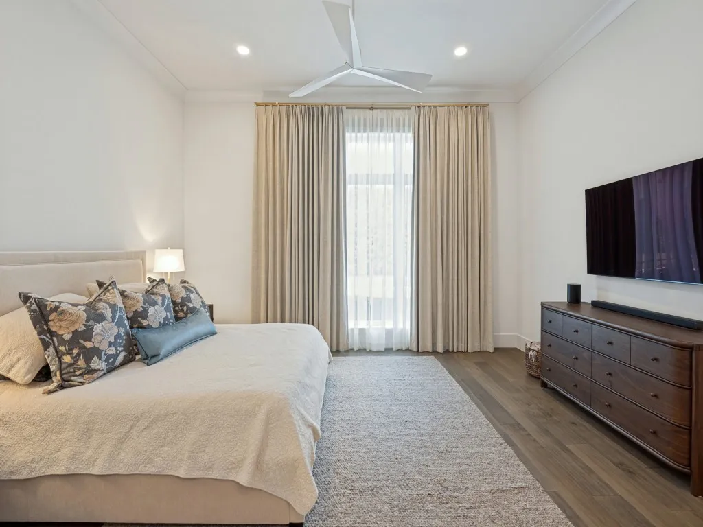 Primary bedroom features good natural light and a modern ceiling fan.