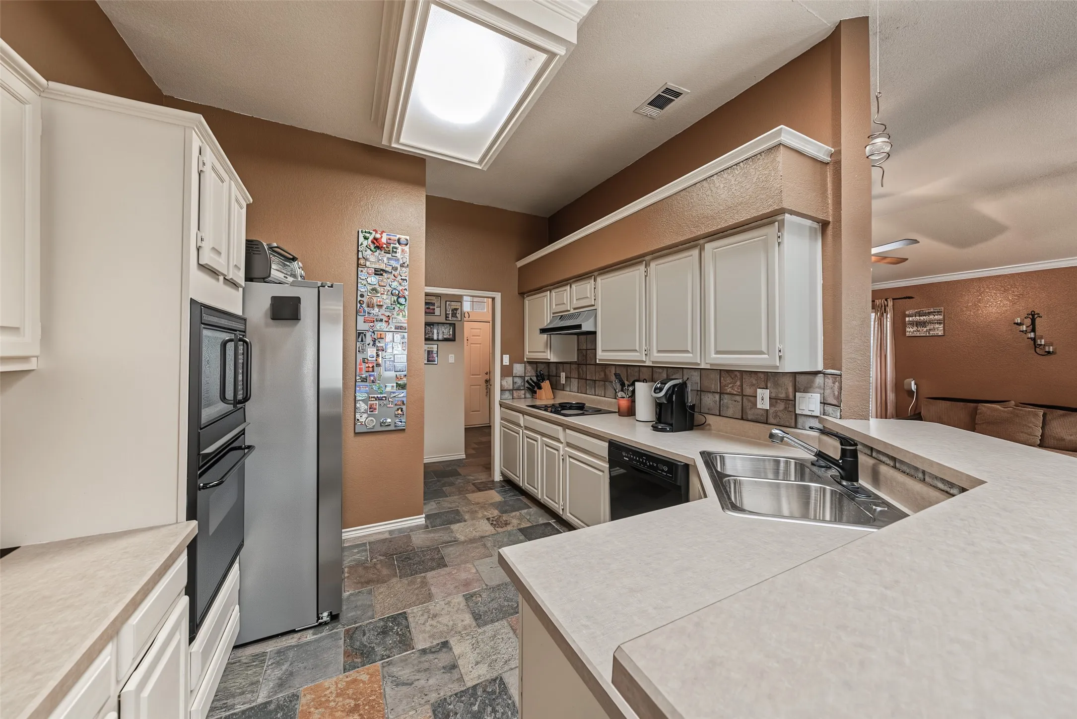 Kitchen featuring white cabinetry, an integrated double oven, and a double basin sink