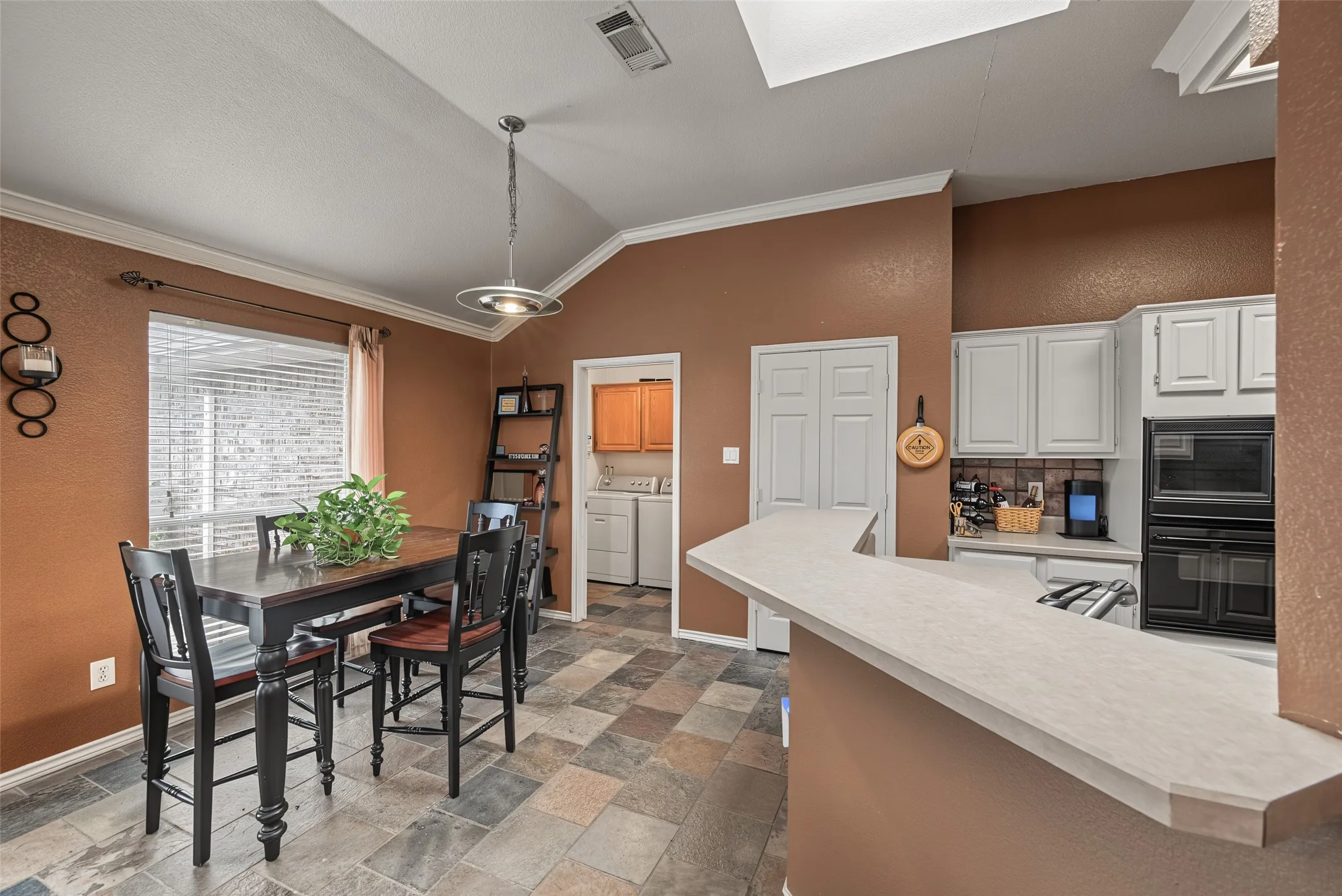 Kitchen featuring white cabinetry, built-in double ovens, and a breakfast bar