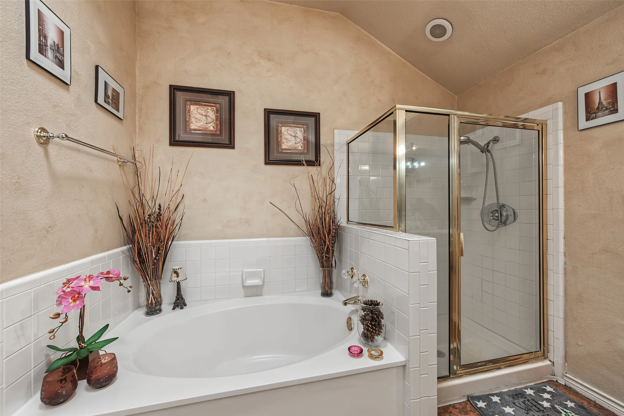 Corner soaking tub, separate glass-enclosed shower, white tile surround, and vaulted ceiling