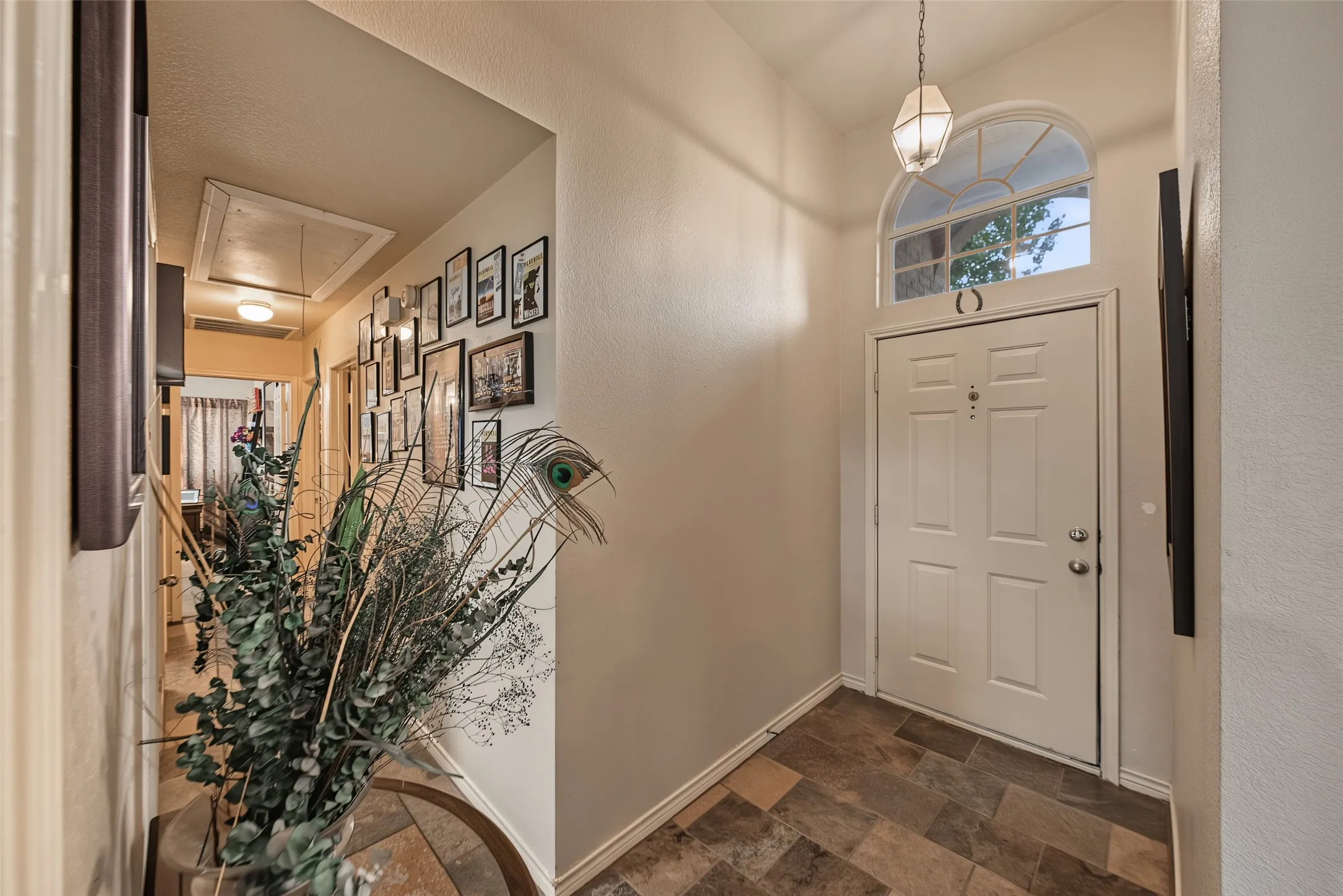 Entryway featuring a white paneled door with an arched transom window, slate-look tile flooring, and a decorative pendant light fixture