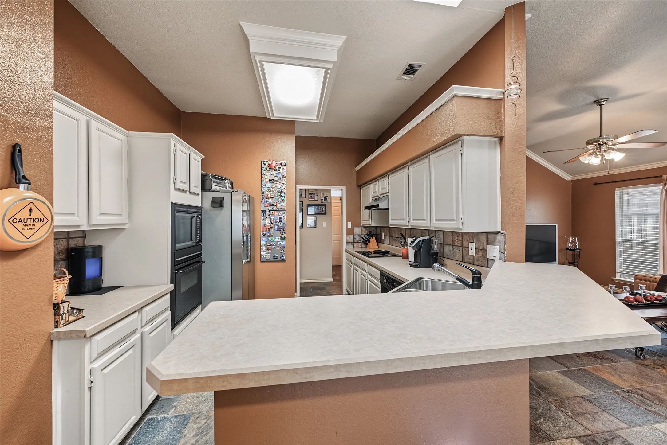 Kitchen featuring white cabinetry, light-colored countertops, built-in double oven, and tile flooring