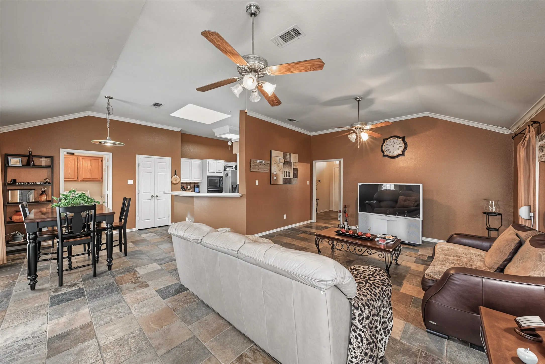 Vaulted ceilings with exposed beams, multiple ceiling fans, and a skylight illuminate the space