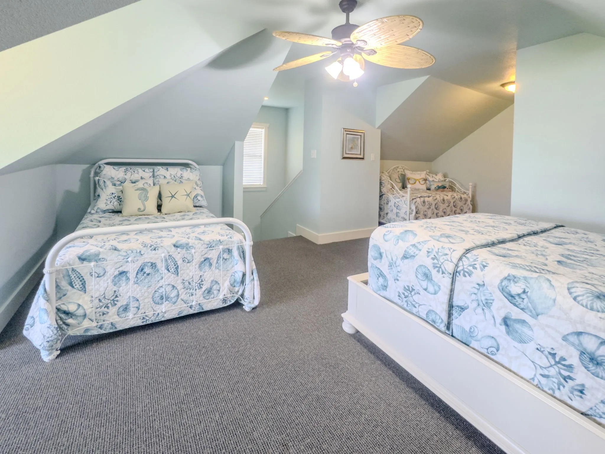 Carpeted attic space with sloped ceilings and a ceiling fan