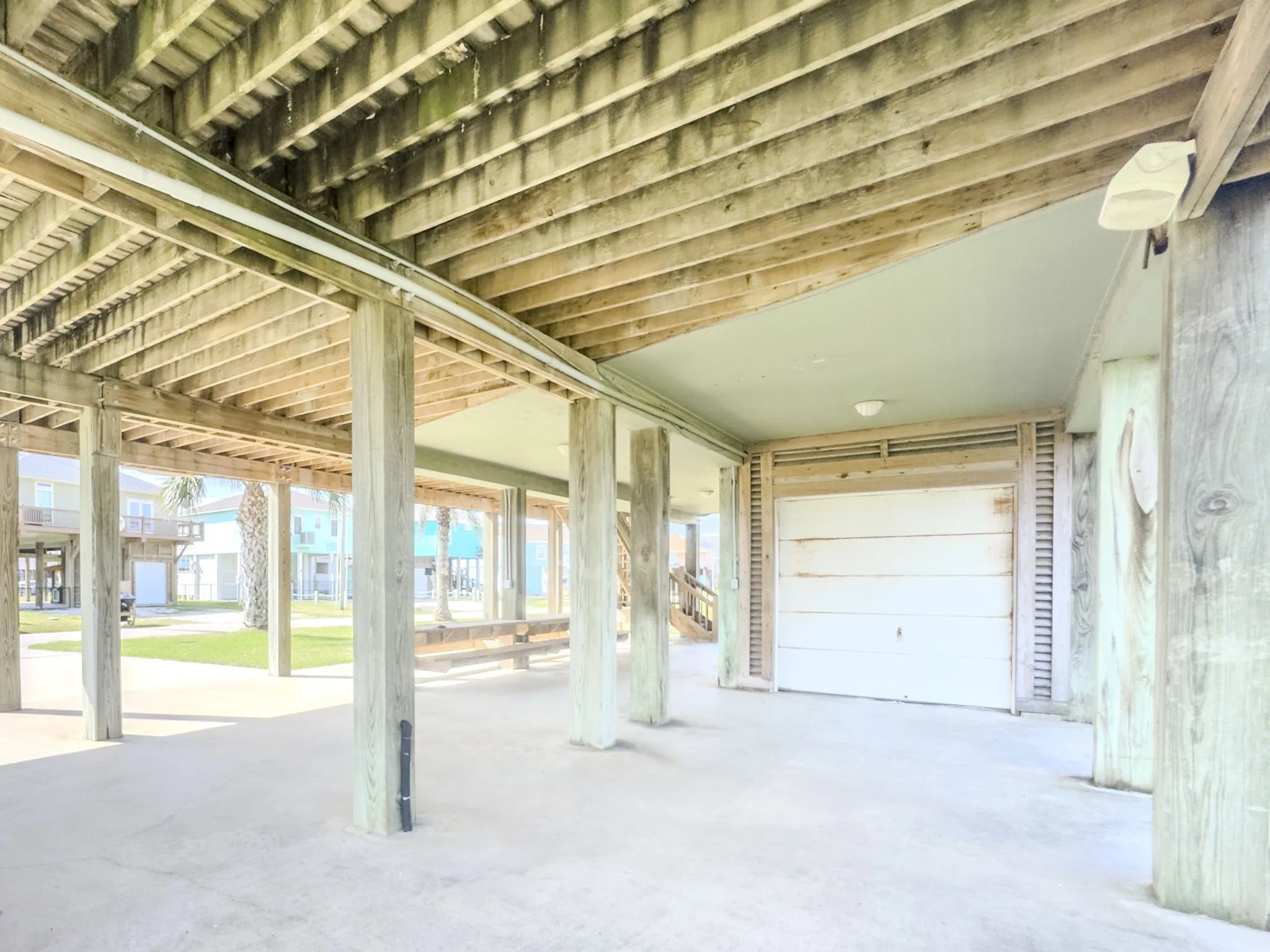 Spacious covered structure with exposed wood beam ceiling, concrete flooring, and multiple support columns