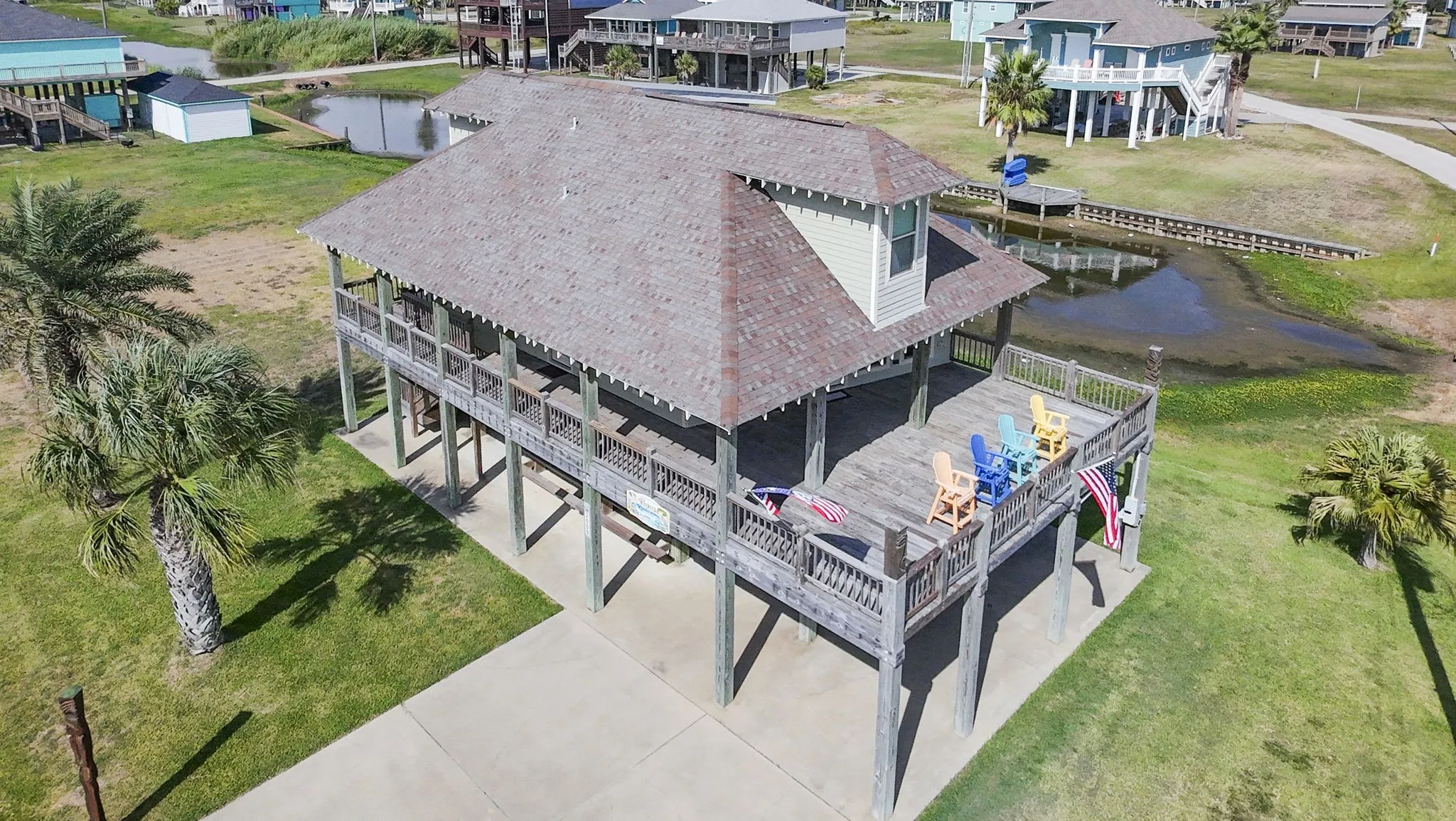 Expansive elevated deck with wood railings, a dock, and mature palm trees