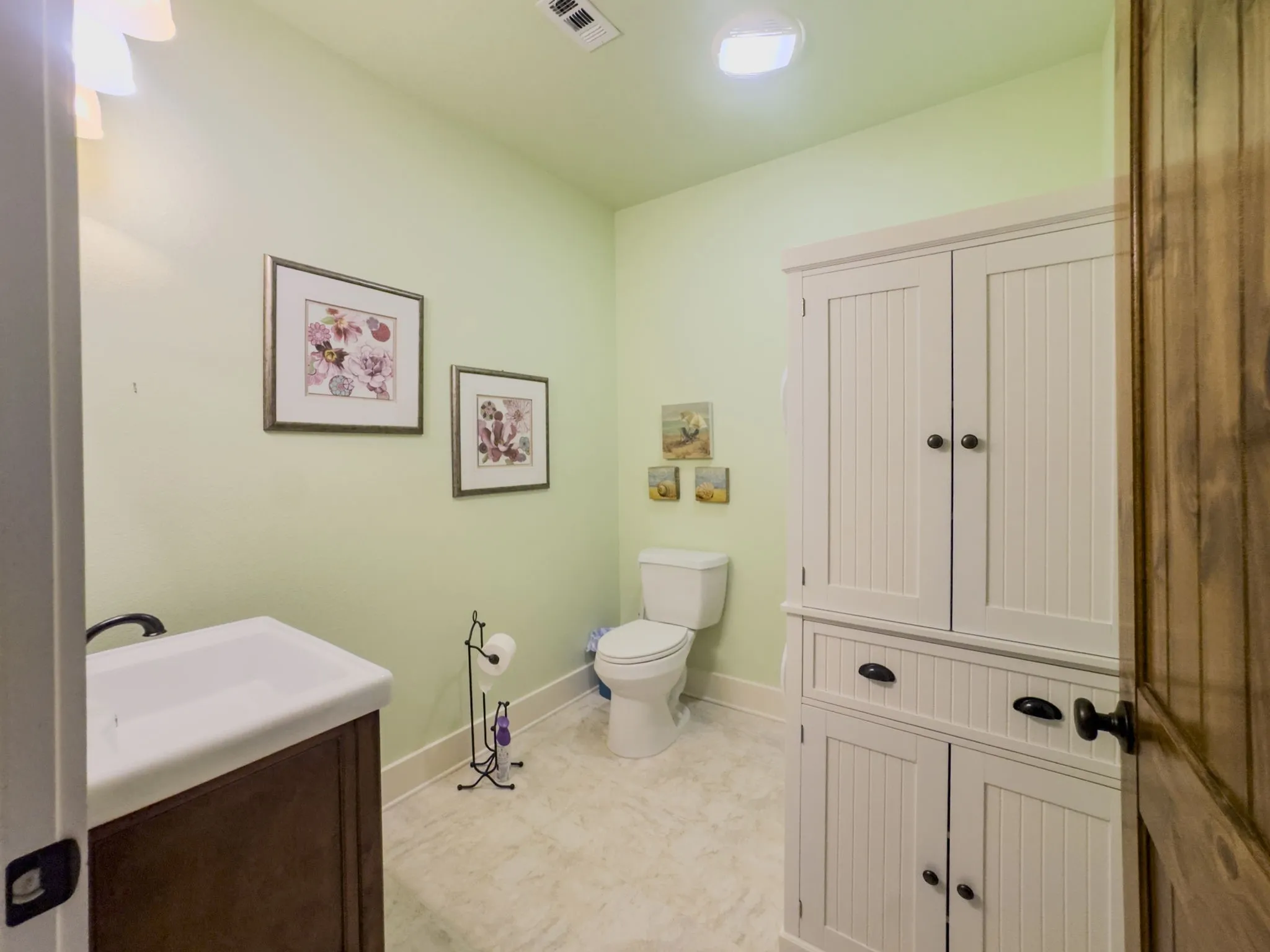 White panel-style storage cabinetry, built-in vanity with integrated sink, and light-toned flooring