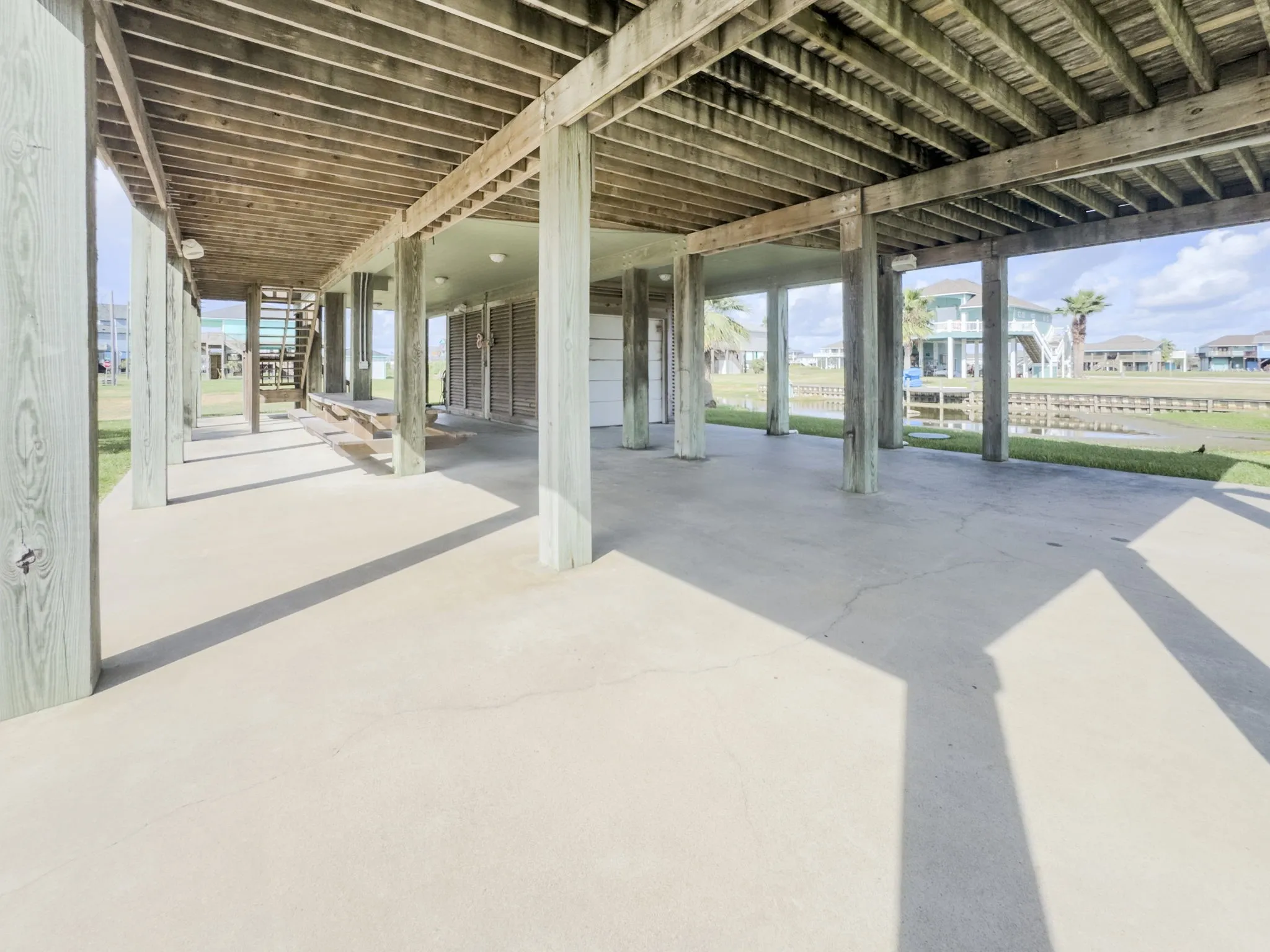 Concrete slab patio with wood pilings and an exterior staircase