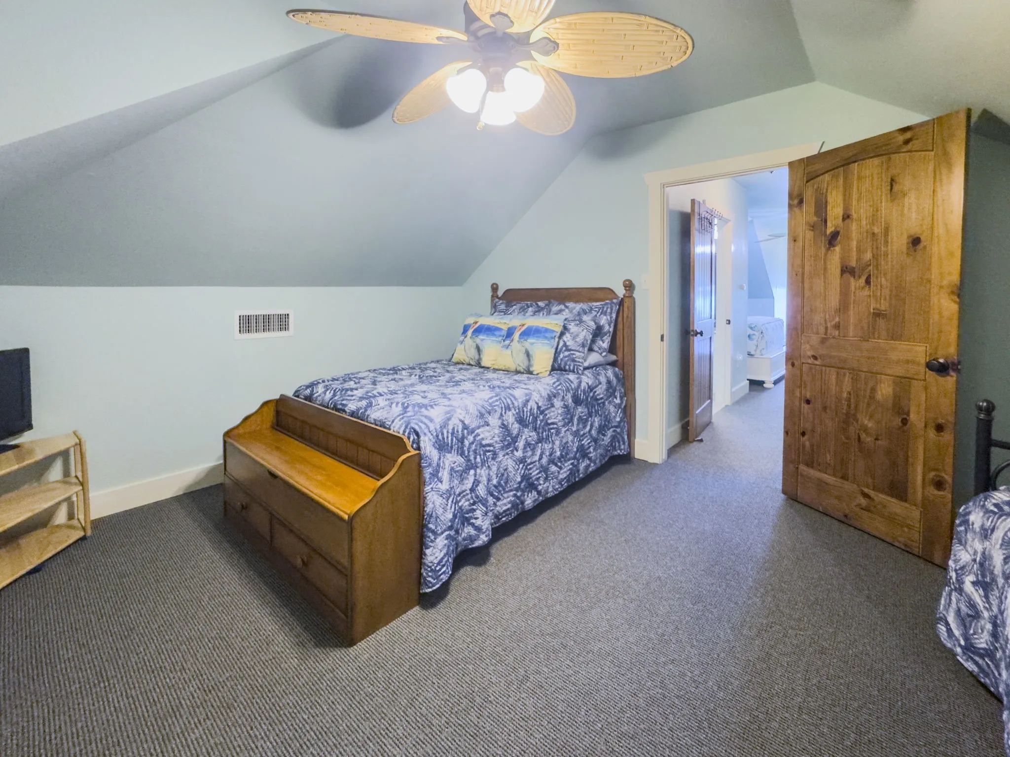 Vaulted ceiling with a ceiling fan, plank-style wood door, and grey textured carpeting