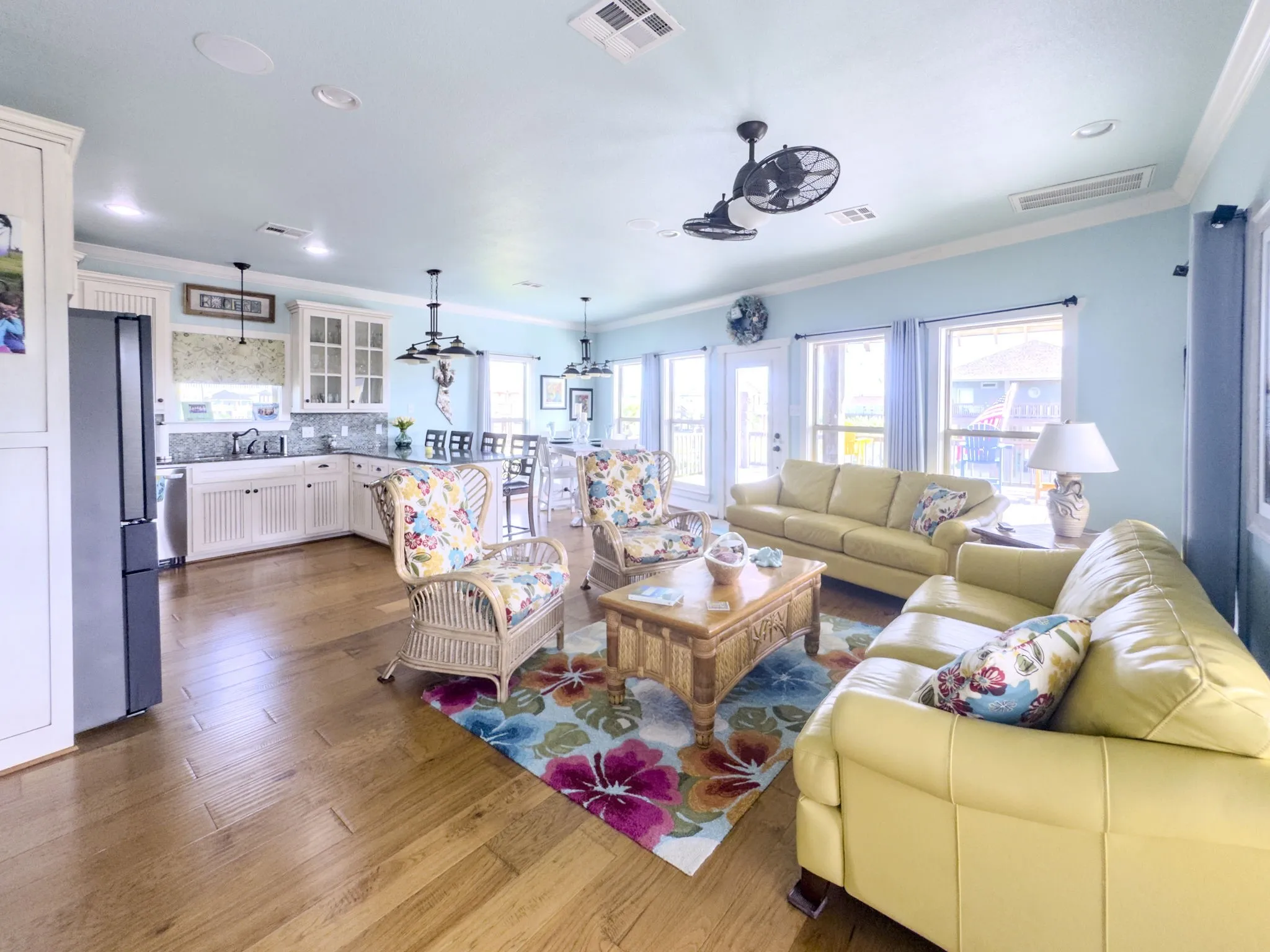 Open-concept living area with wood-finish flooring, white shaker cabinetry, and multiple large windows