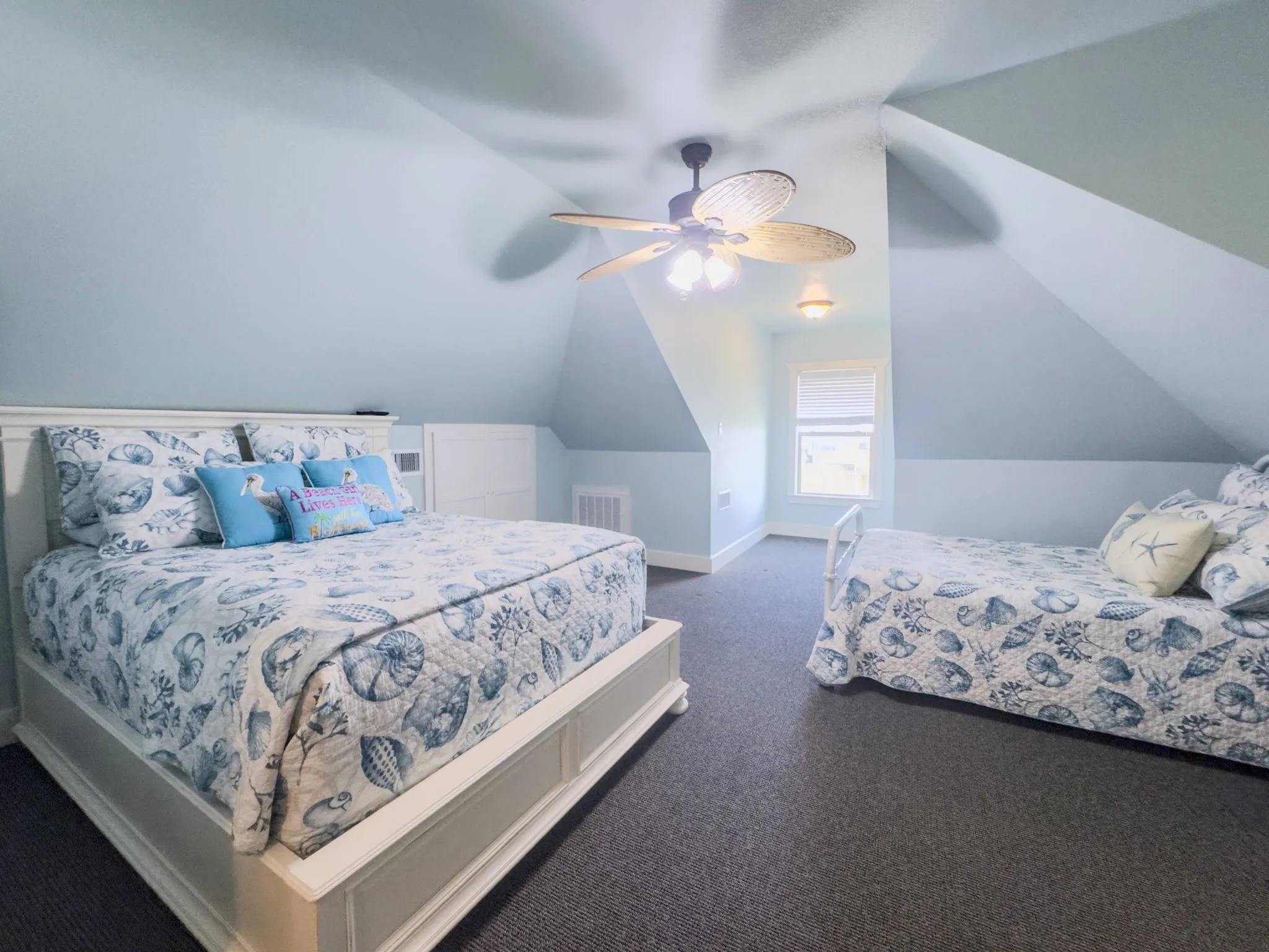 Sloped ceilings, ceiling fan with integrated lighting, built-in storage, and a fixed window provide functional design elements