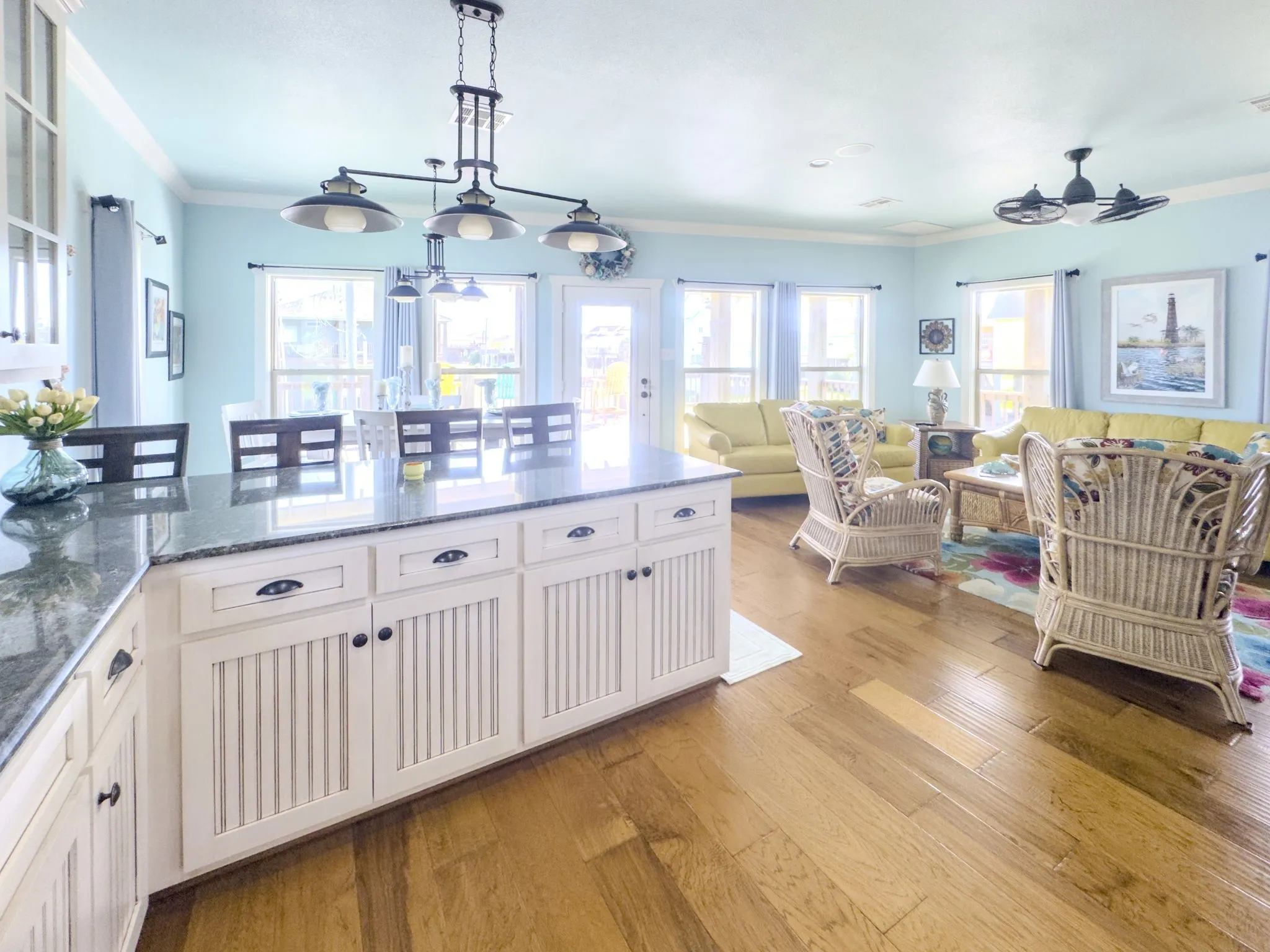 Kitchen island with granite-finish countertop, white cabinetry with black hardware, and wood-finish flooring throughout