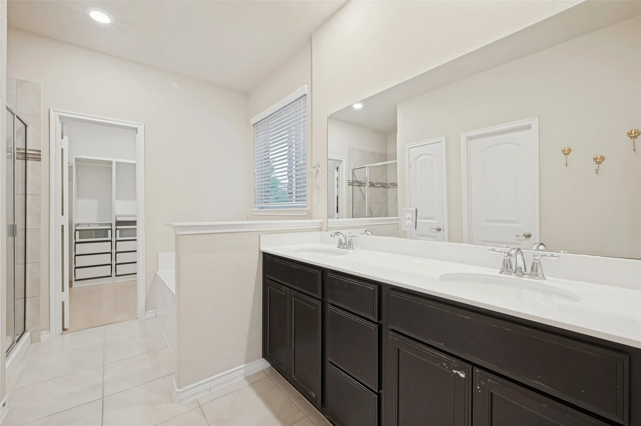 Double vanity with undermount sinks, separate shower, and walk-in closet with built-in organization