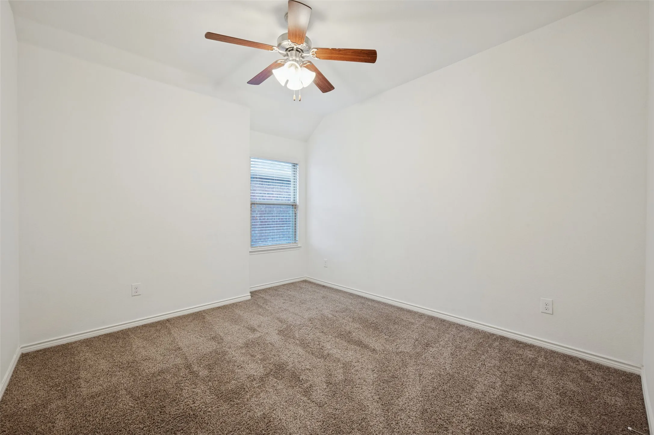 Neutral wall paint, textured carpeting, window with blinds, ceiling fan with integrated lighting