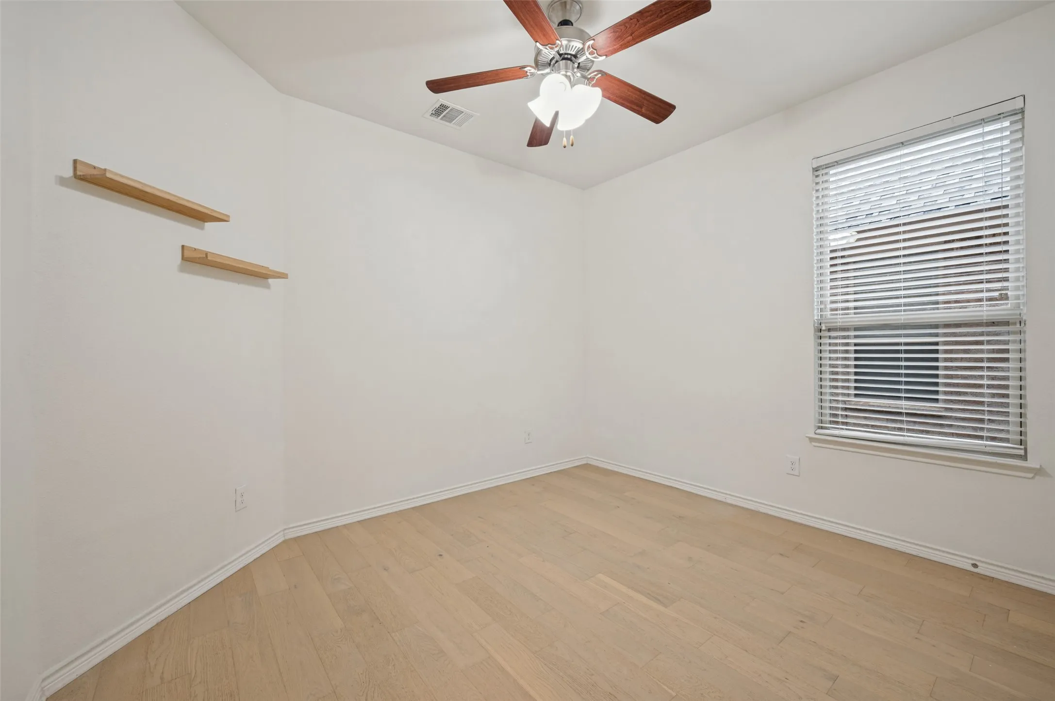 Light wood-finish flooring, a ceiling fan with light fixture, and a window with blinds