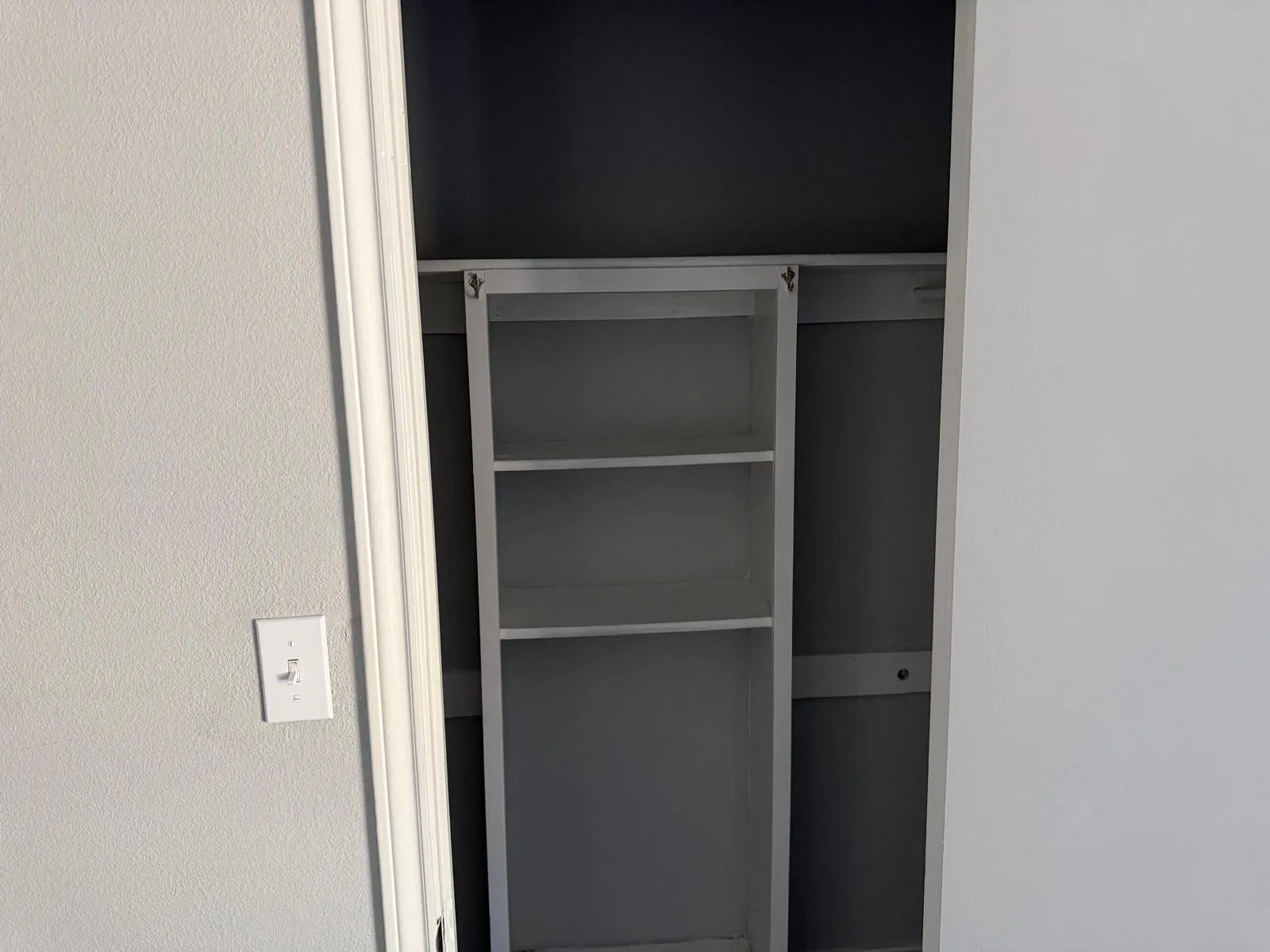 Built-in shelving unit with three storage compartments and an integrated hanging rod