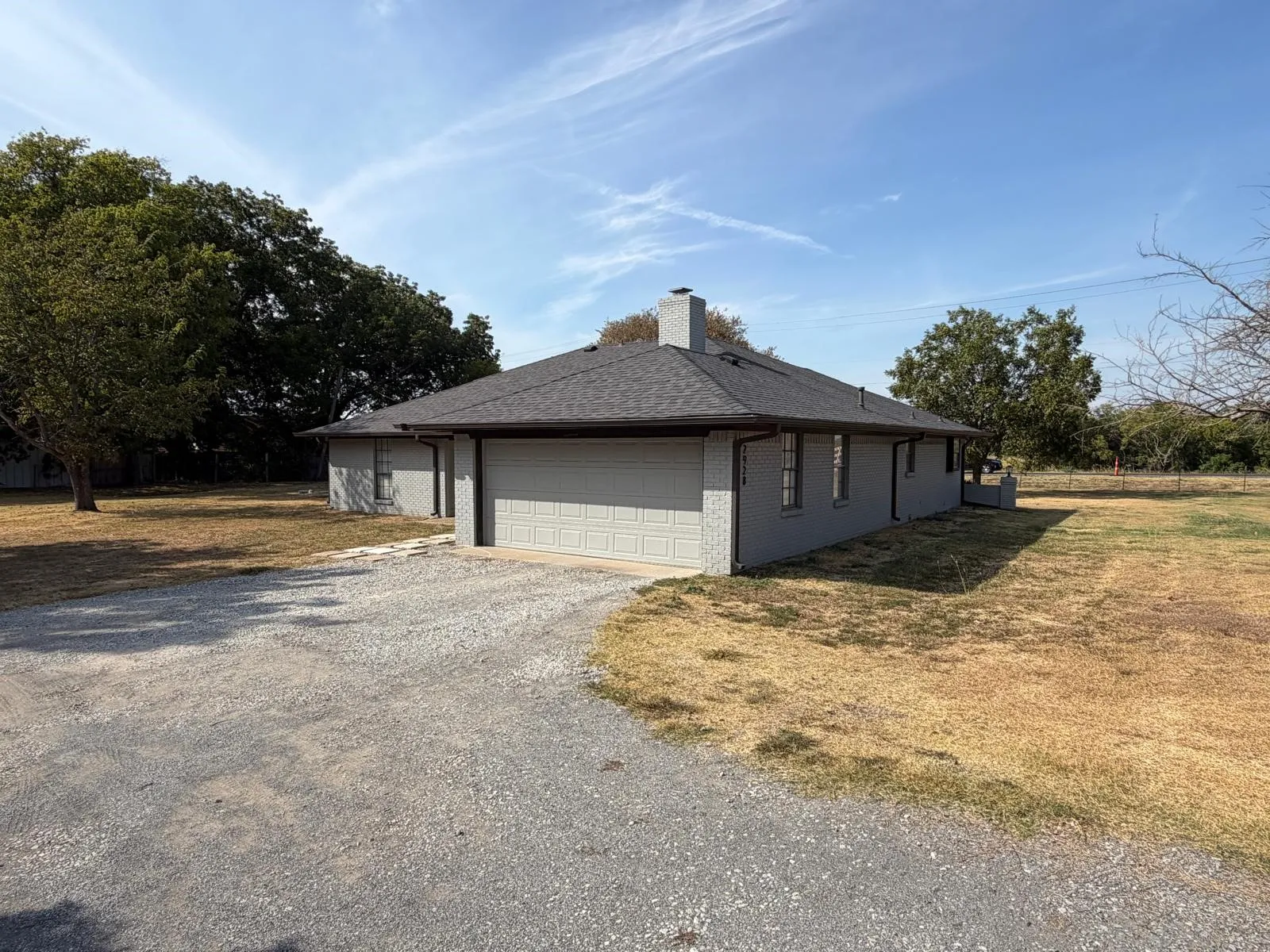 Gray brick exterior with a dark shingle roof and an attached garage