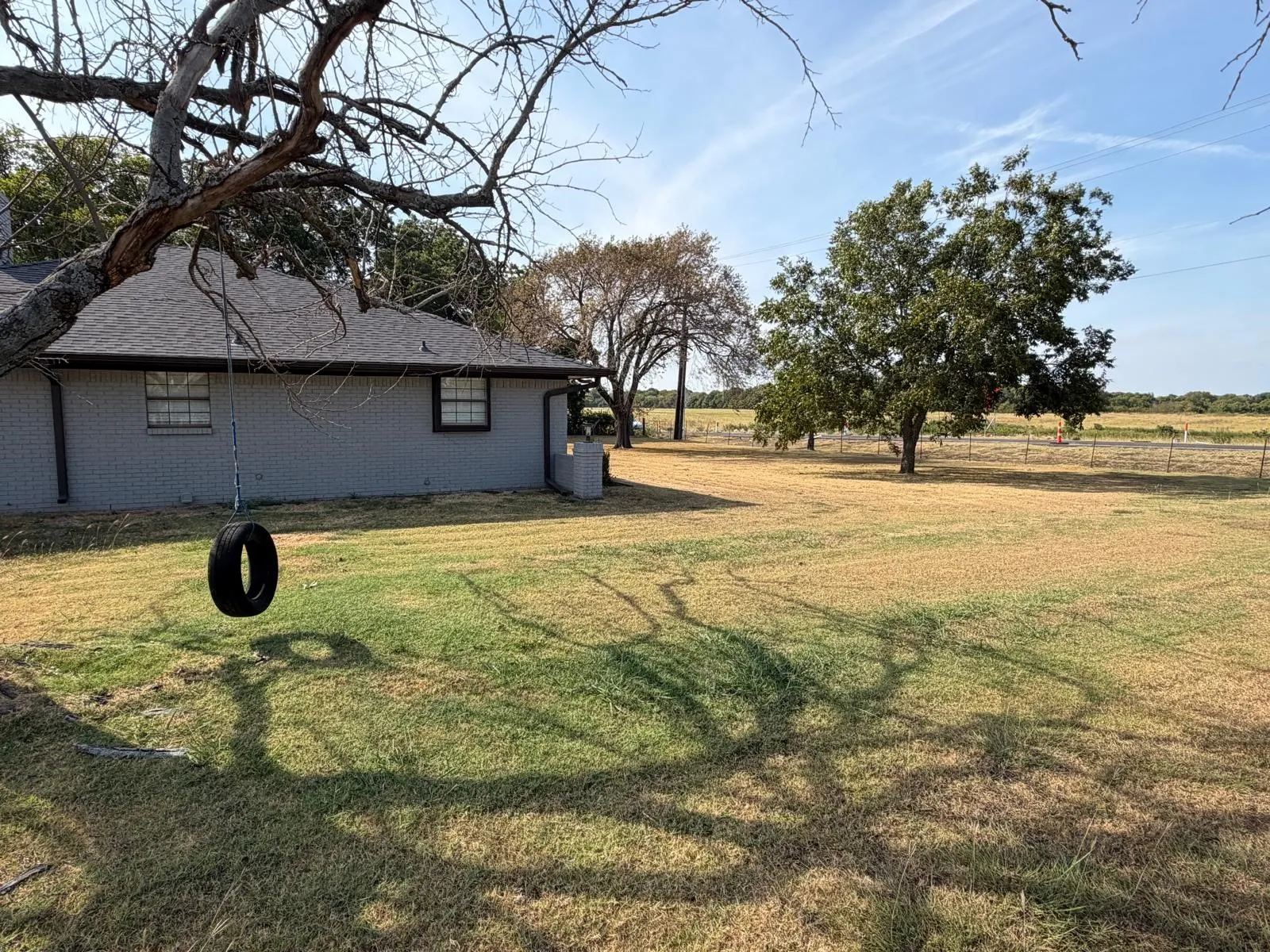 Expansive lawn with mature trees and a fenced perimeter