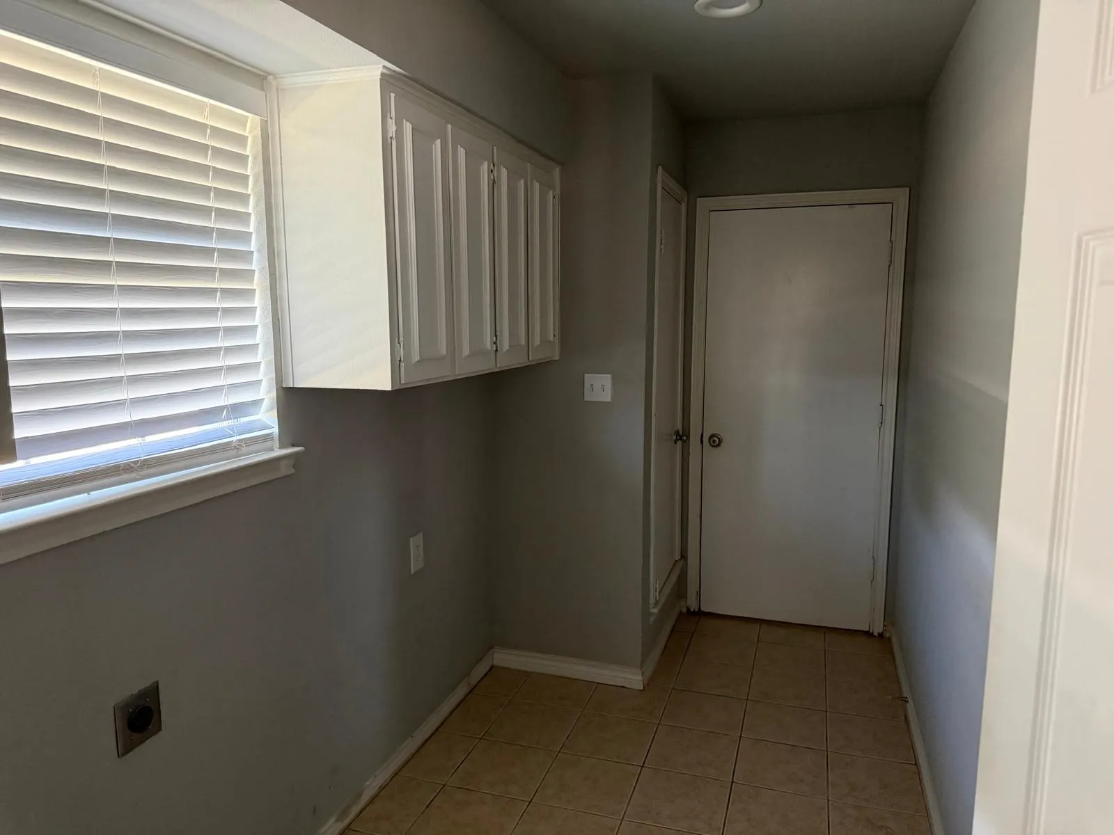 Window with horizontal blinds, overhead cabinetry, recessed lighting, and tile flooring
