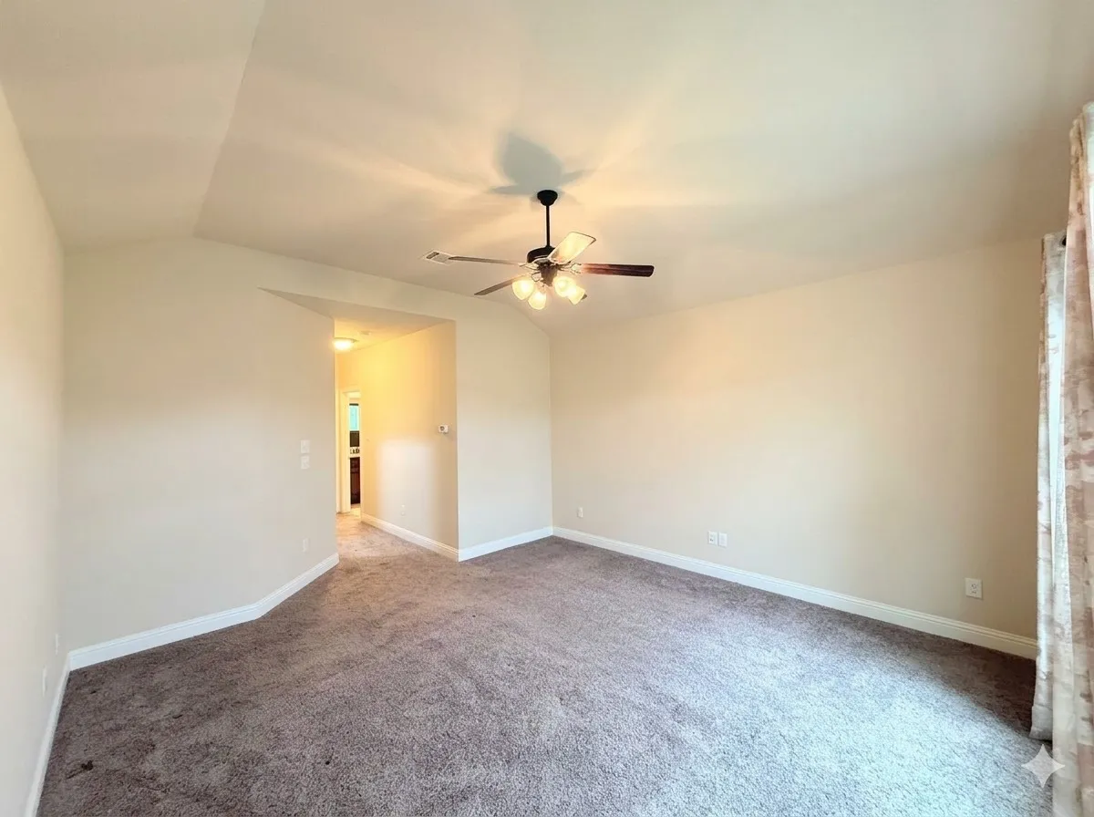 Tray ceiling, ceiling fan with light fixture, carpet flooring, neutral wall tones, interior passageway