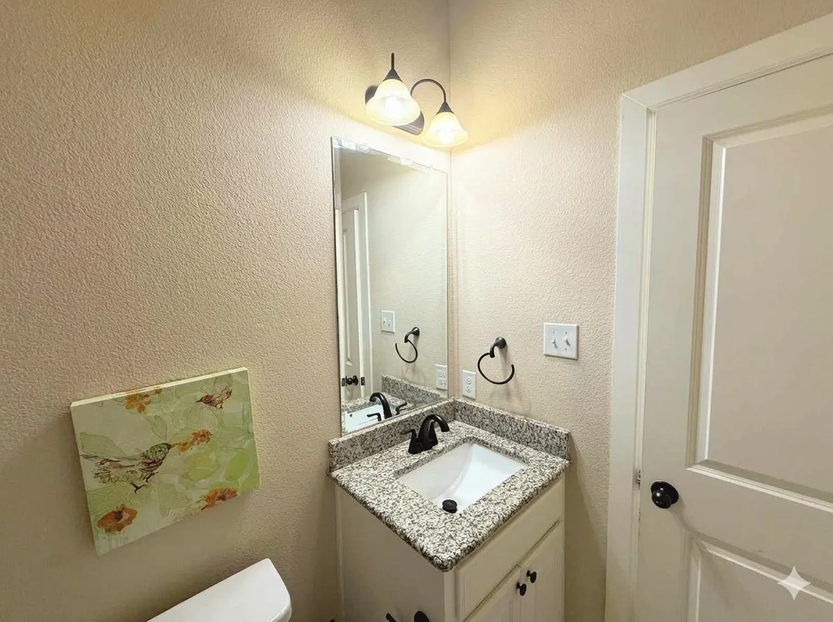 Vanity with a granite-style countertop, undermount sink, and black faucet