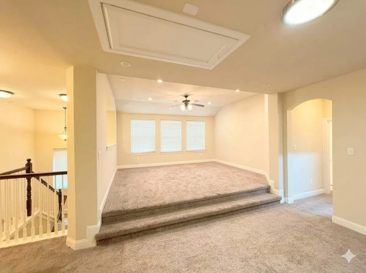 Multi-level interior featuring a carpeted raised platform, vaulted ceiling, and recessed lighting