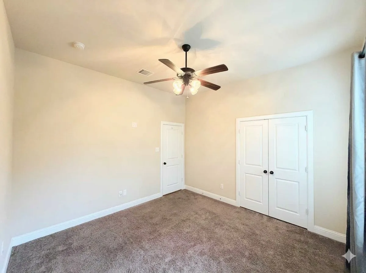 Vaulted ceiling with a ceiling fan light fixture, wall-to-wall carpeting, and white trim