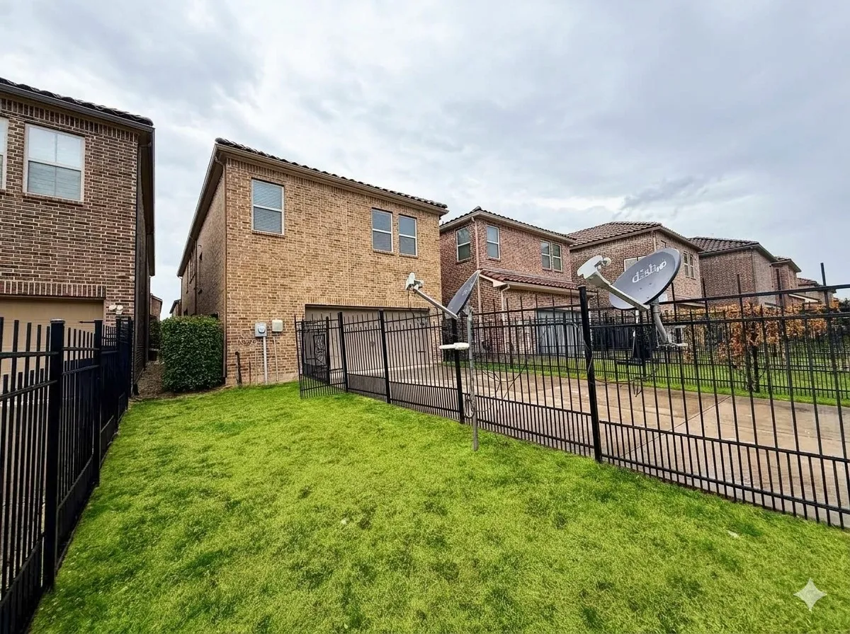 Manicured lawn area with black wrought iron fencing